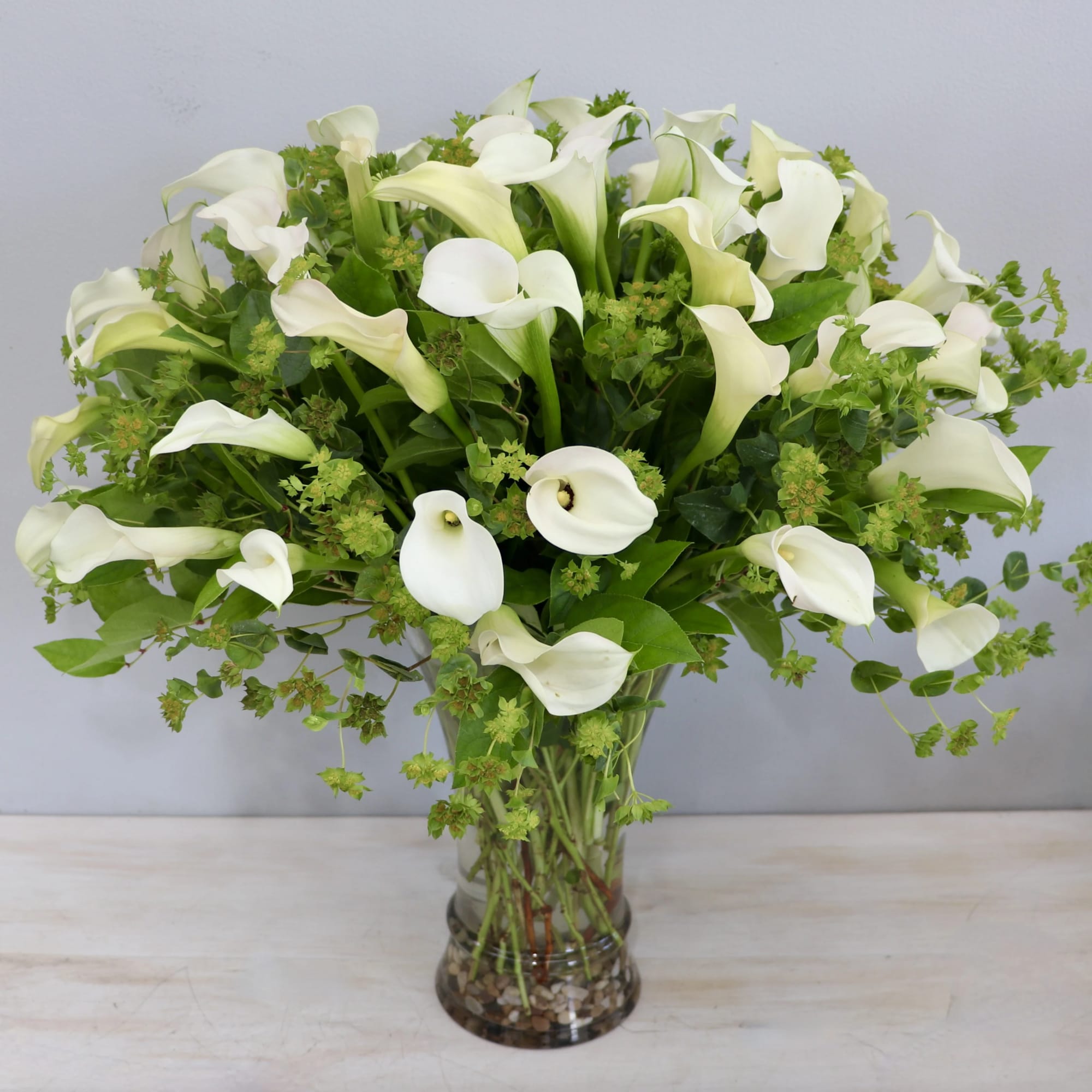 This floral arrangement features a stunning display of all-white calla lilies. These