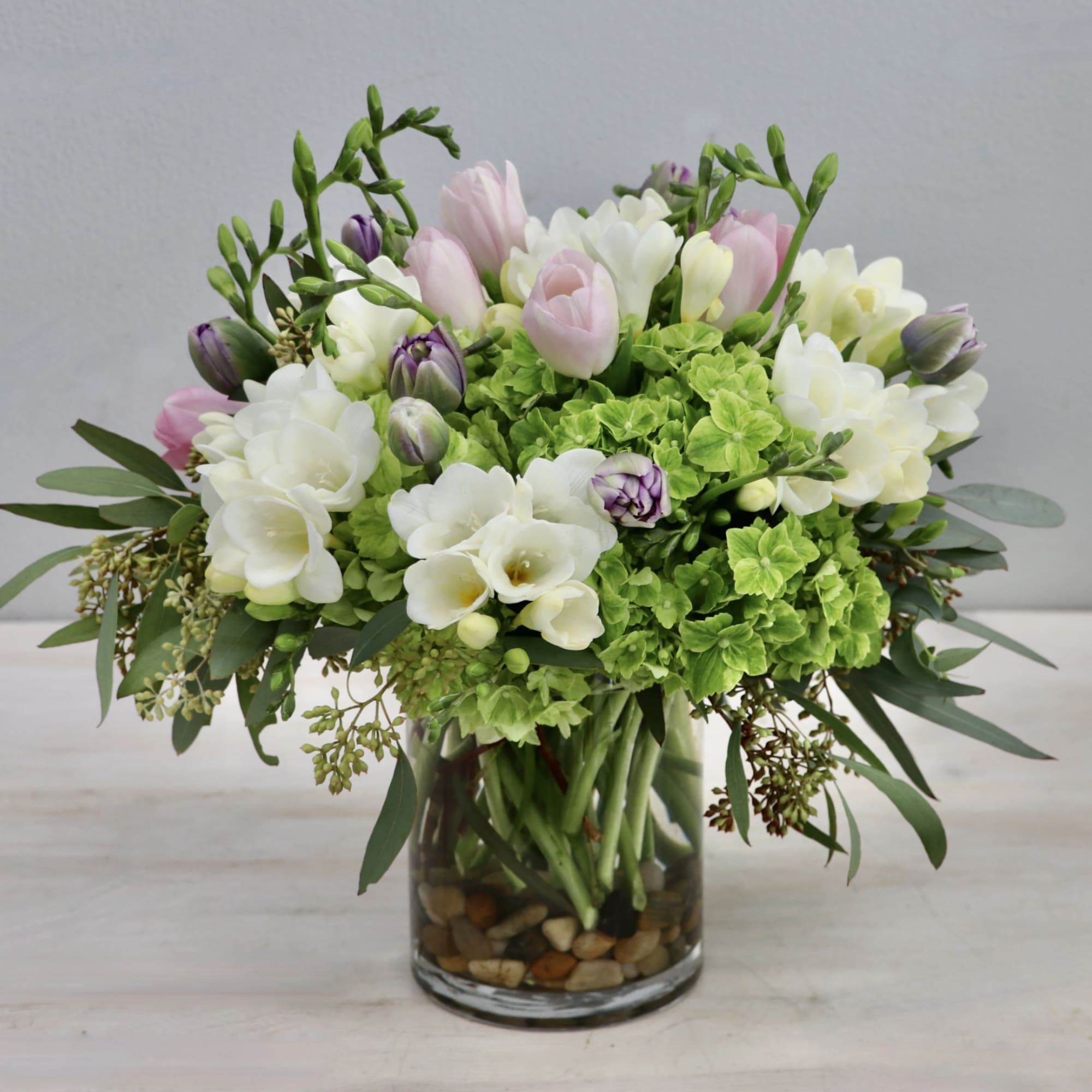 This simple yet sweet arrangement mixes fragrant freesia, tulips, and hydrangeas for