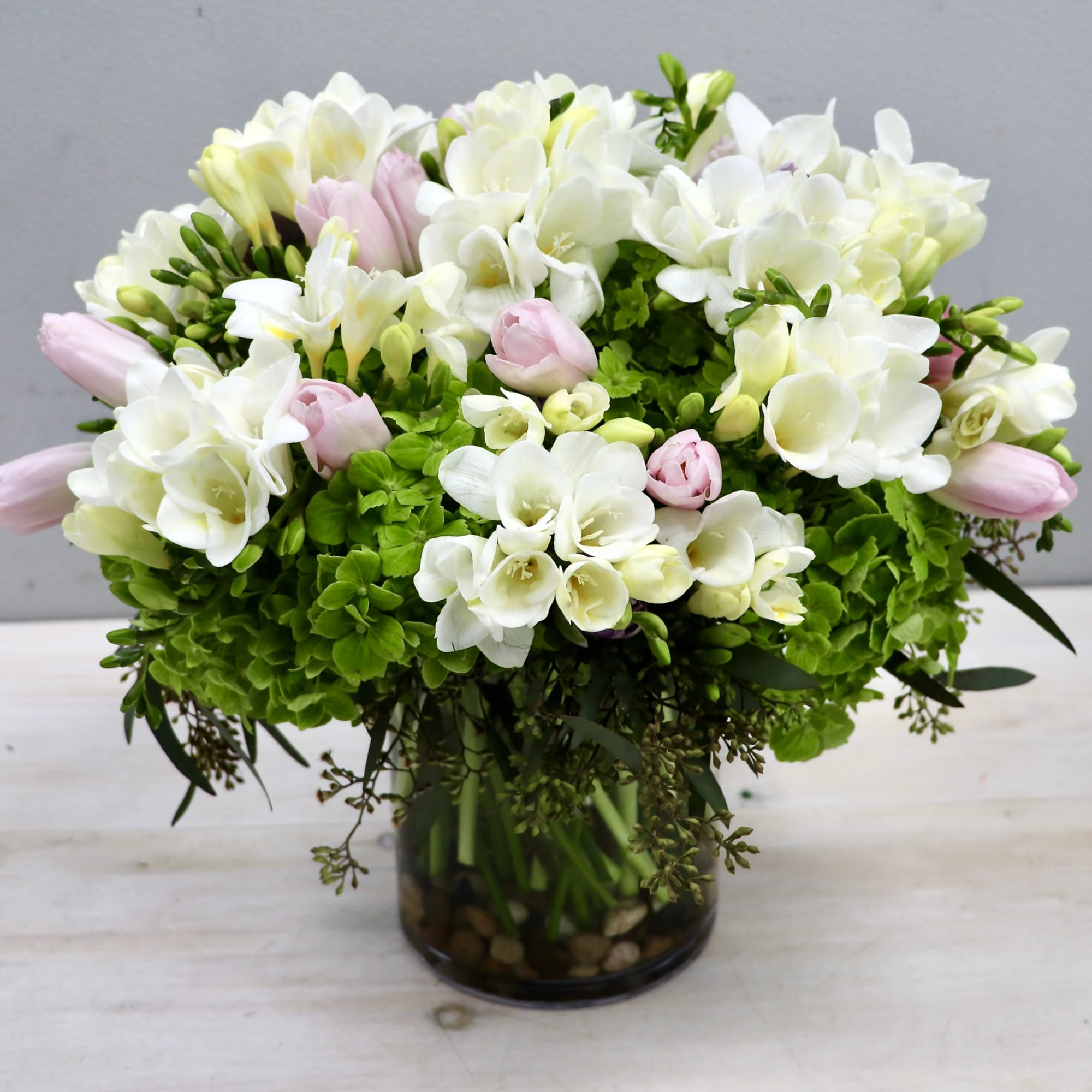 This simple yet sweet arrangement mixes fragrant freesia, tulips, and hydrangeas for