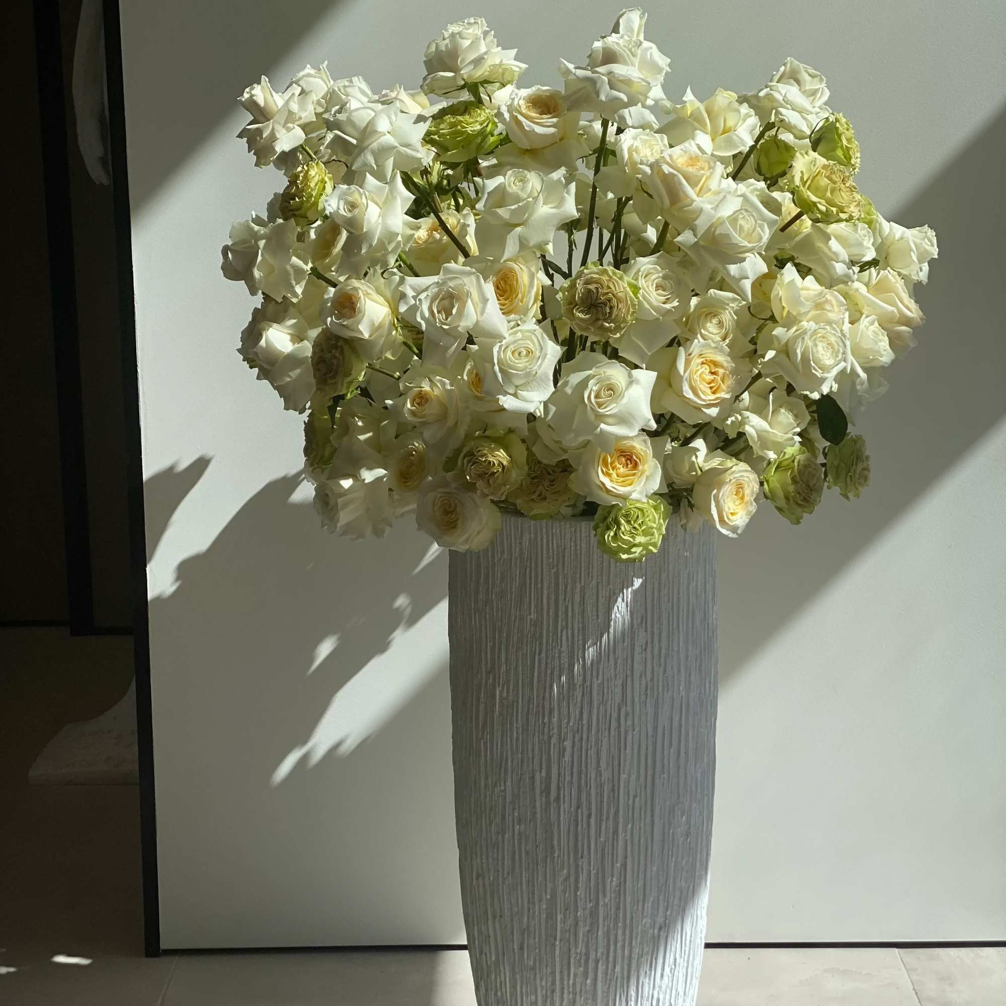 White and beige roses beautifully arranged in a high vase, offering a