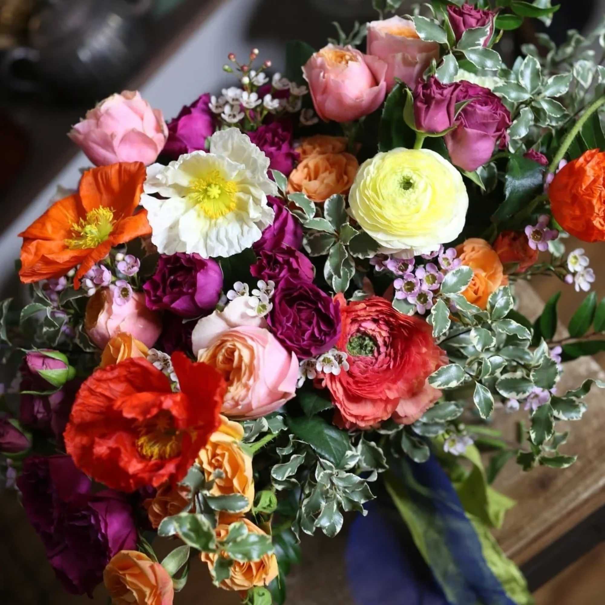 Alisa is a vibrant flower arrangement with poppy flowers, orange roses, ranunculus