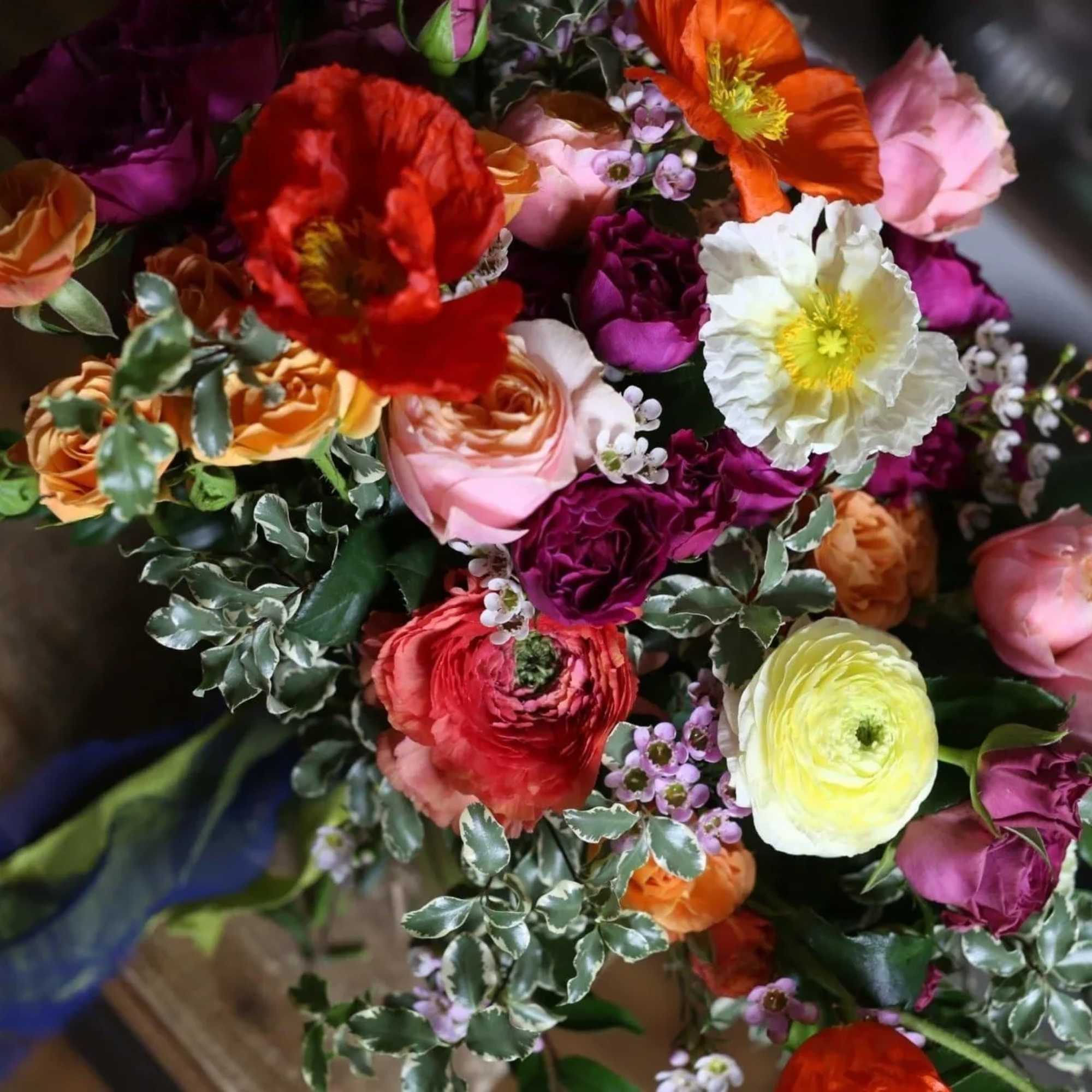 Alisa is a vibrant flower arrangement with poppy flowers, orange roses, ranunculus