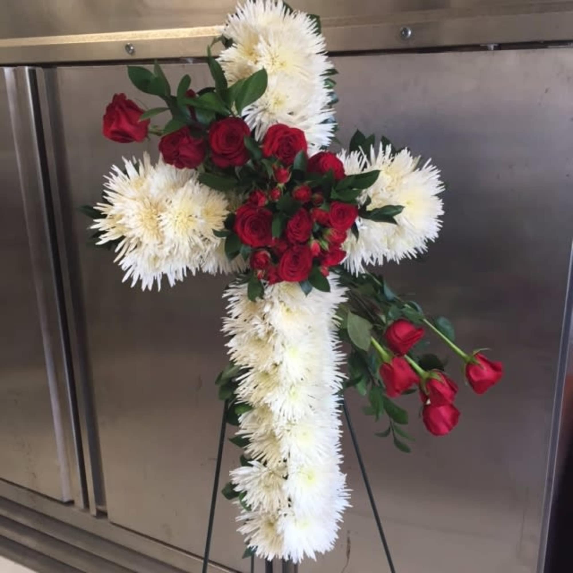 a 22&#039; cross with white spider and red roses in stand

Flowers and