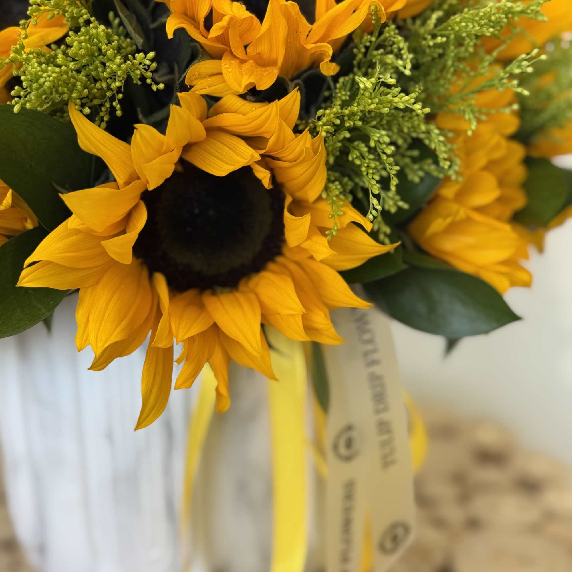 A stunning ceramic vase filled with vibrant sunflowers, complemented by Solidagos. 