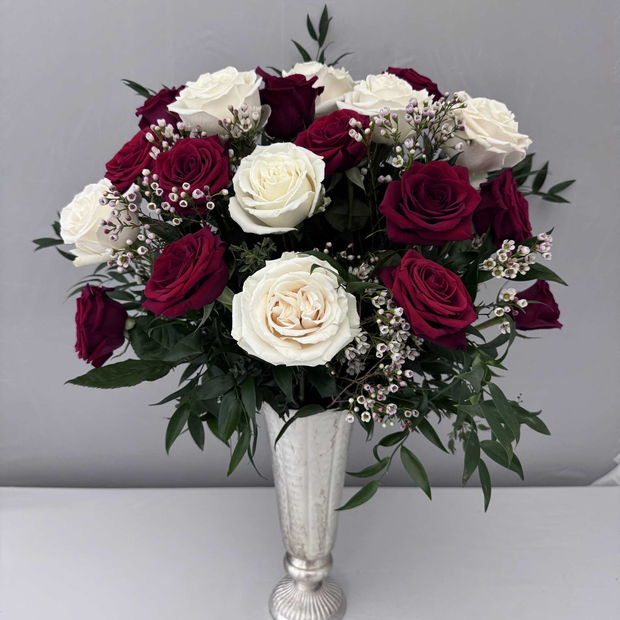 A DOZEN RED AND WHITE ROSES SOPHISTICATELY ARRANGED WITH WHITE WAX FLOWER