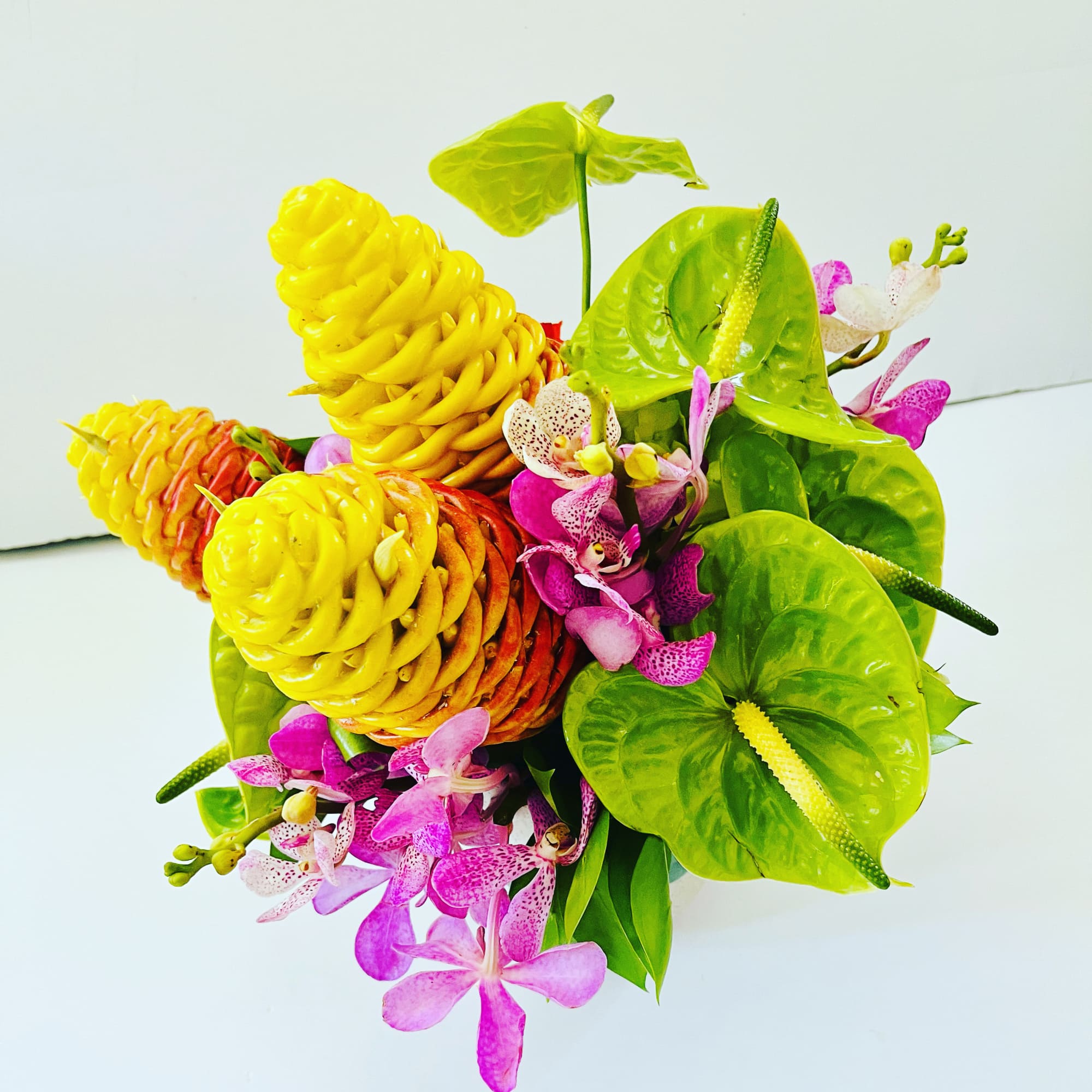 This bright and cheery arrangment is combination of three tropical blooms (based