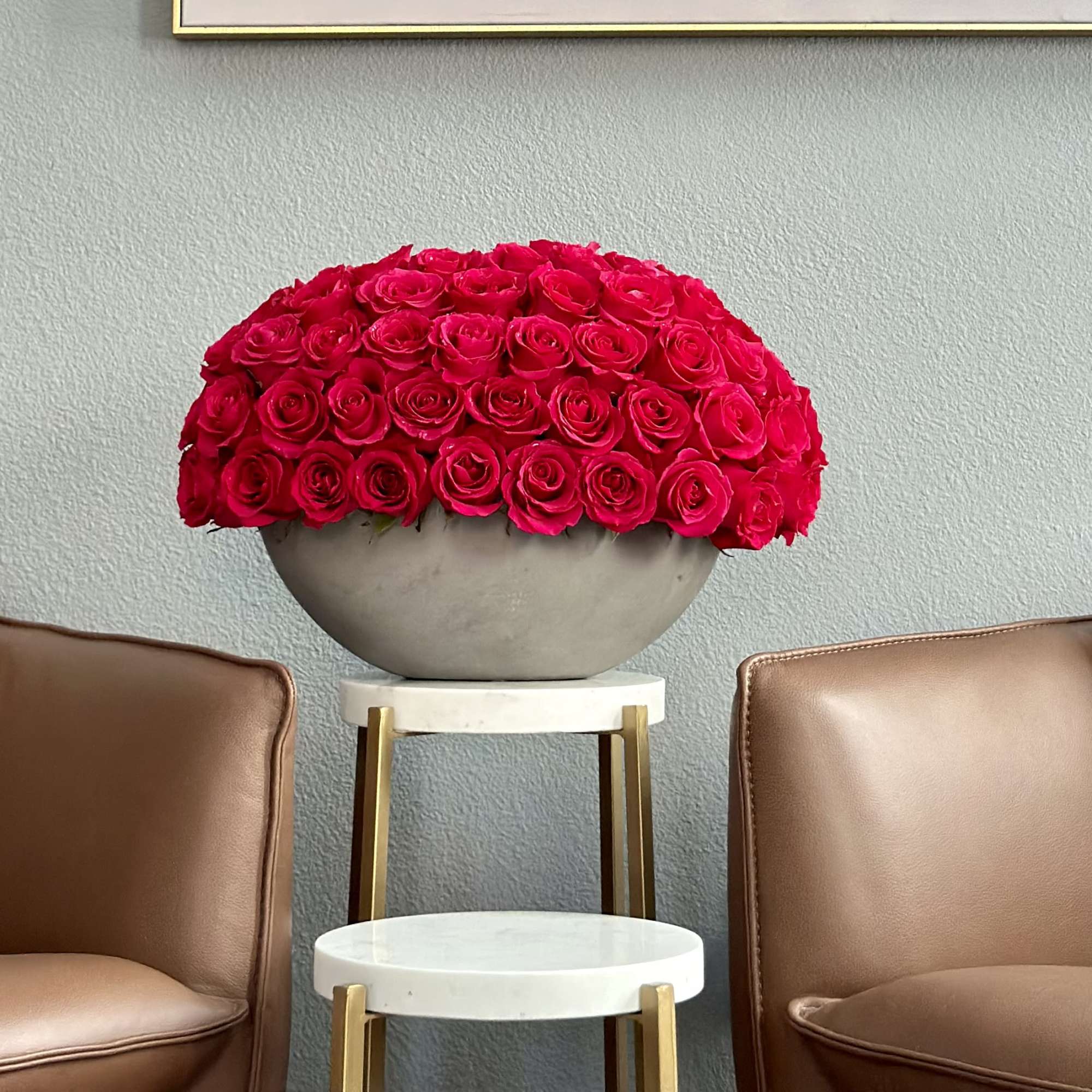 A modern arrangement of 85 premium red roses in a sleek concrete