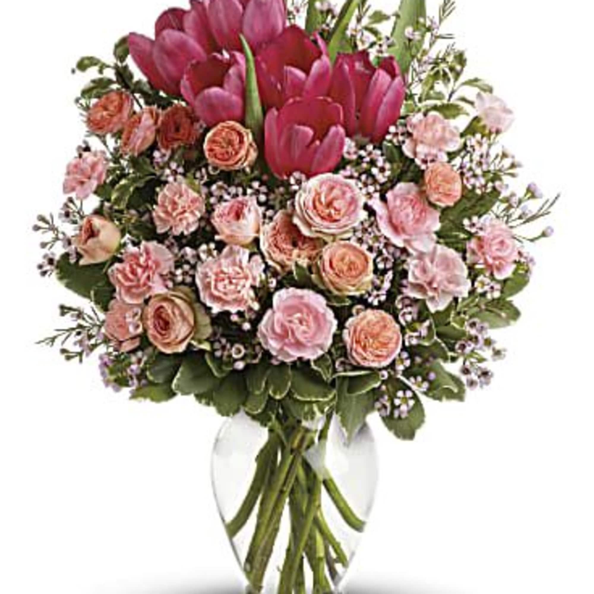 Spring into pink! Delicate roses, tulips and carnations fill a graceful vase Spring into pink! Delicate roses, tulips and carnations fill a graceful vase