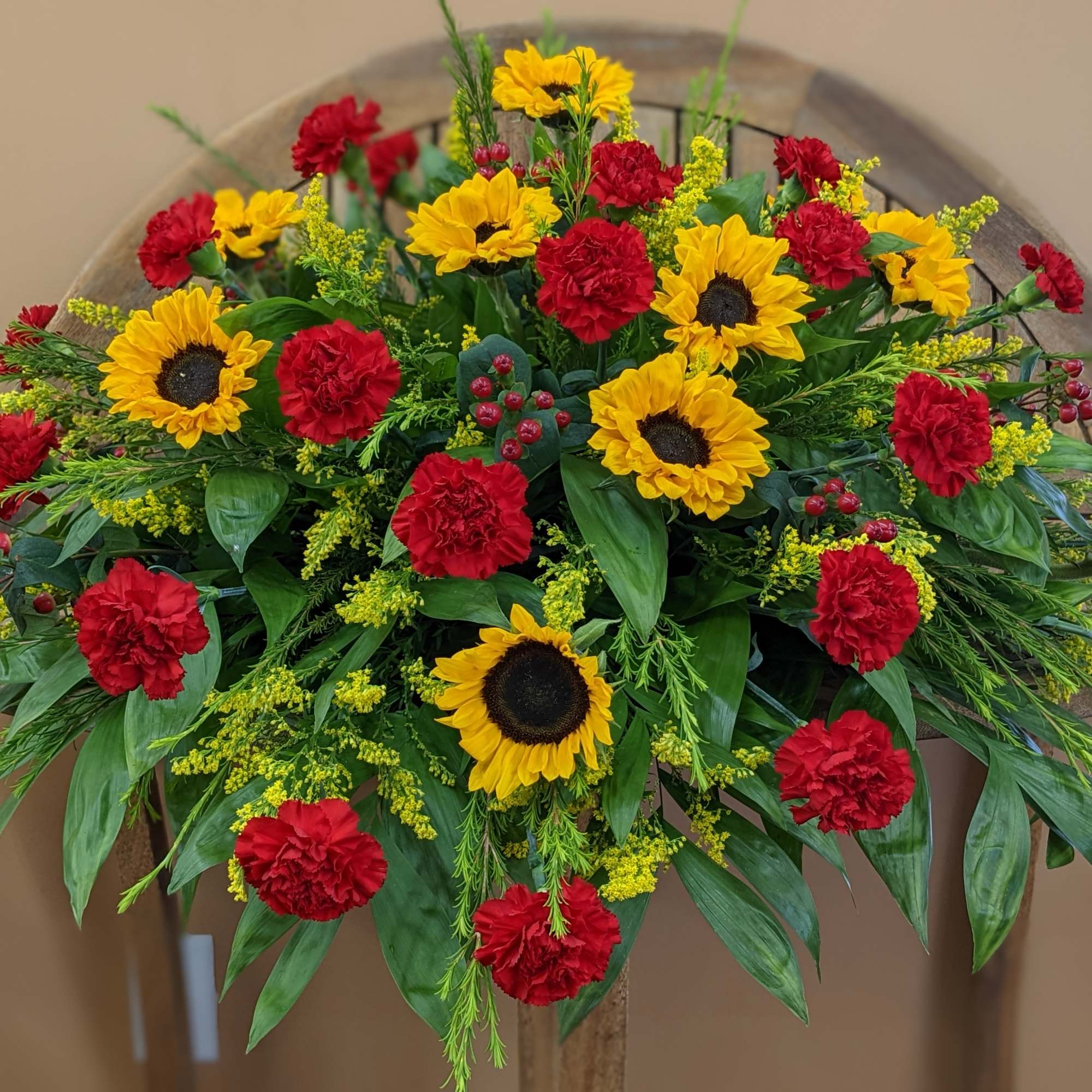 Mixture of sunflower, red carnations, red hypericum, solidago and mixed greens
