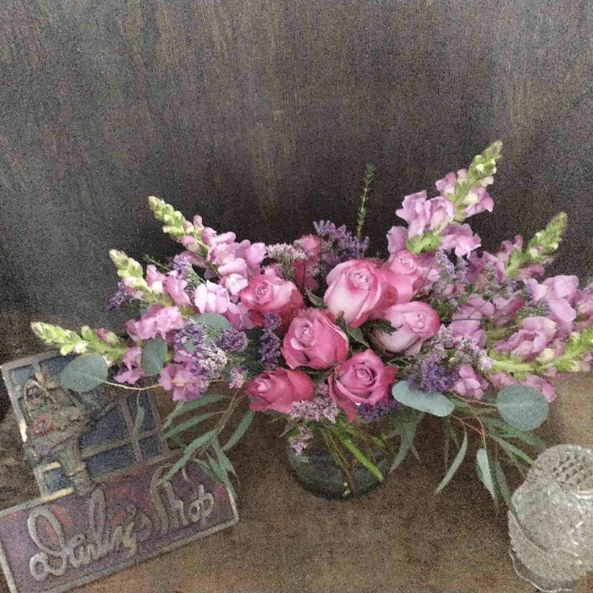 Lavender roses and snapdragons in a low crescent design 