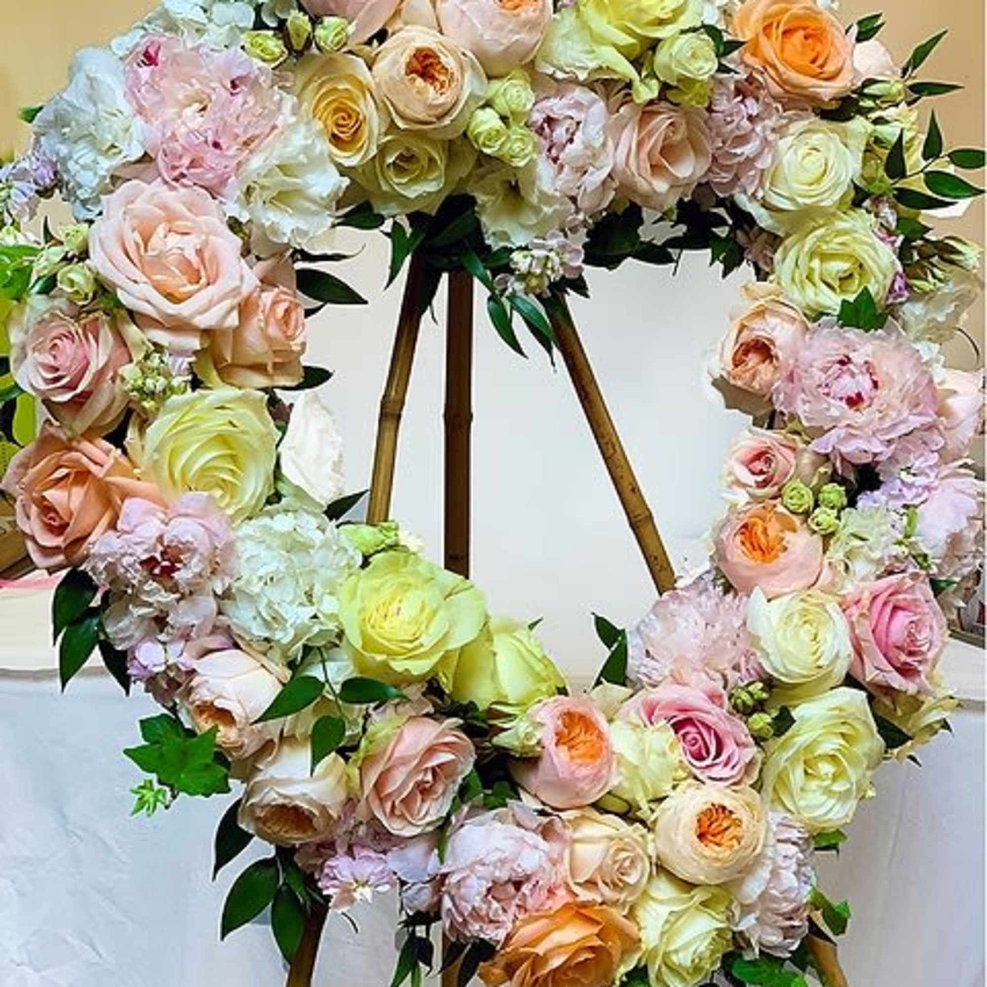 A beautiful heart wreath arranged with soft tones of peaches, pinks, creams