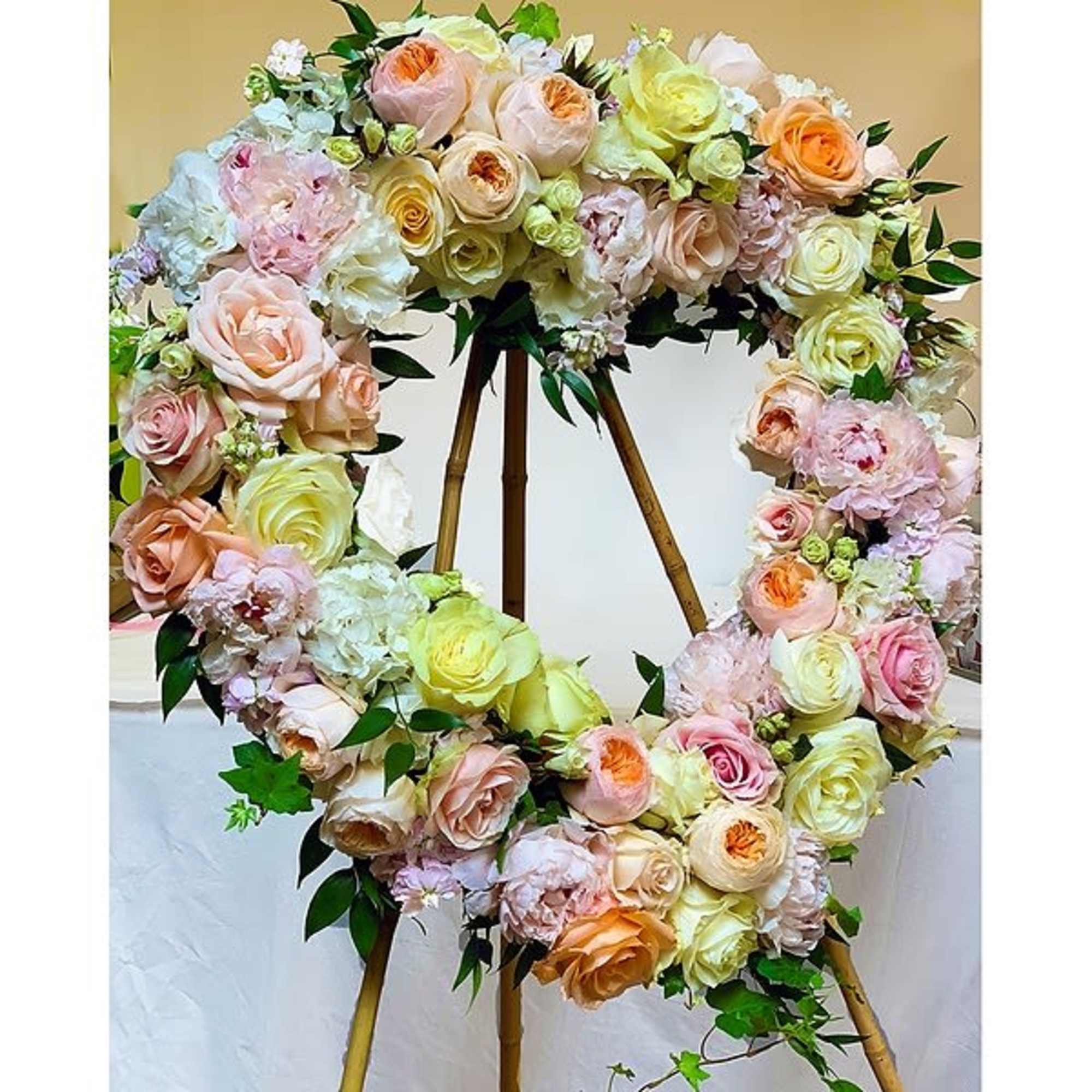 A beautiful heart wreath arranged with soft tones of peaches, pinks, creams