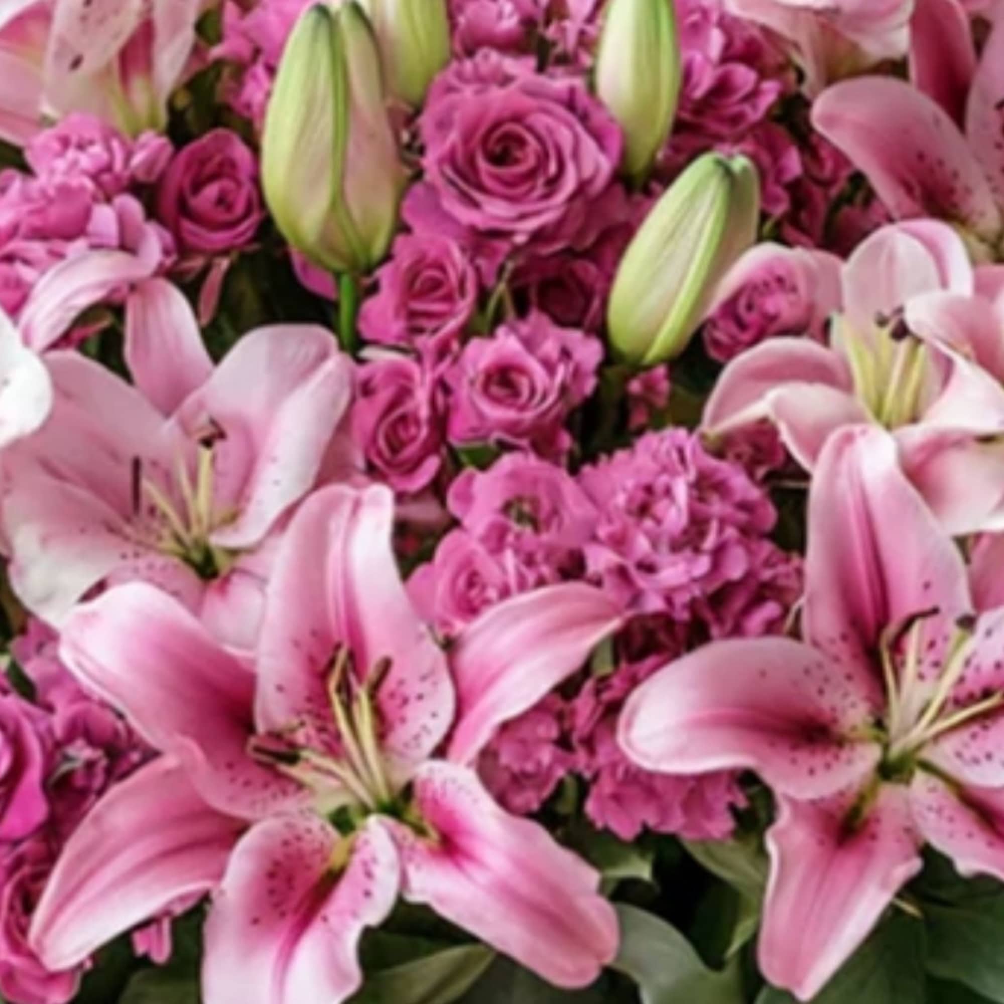 A green basket with a pop of hot pink roses, this arrangement