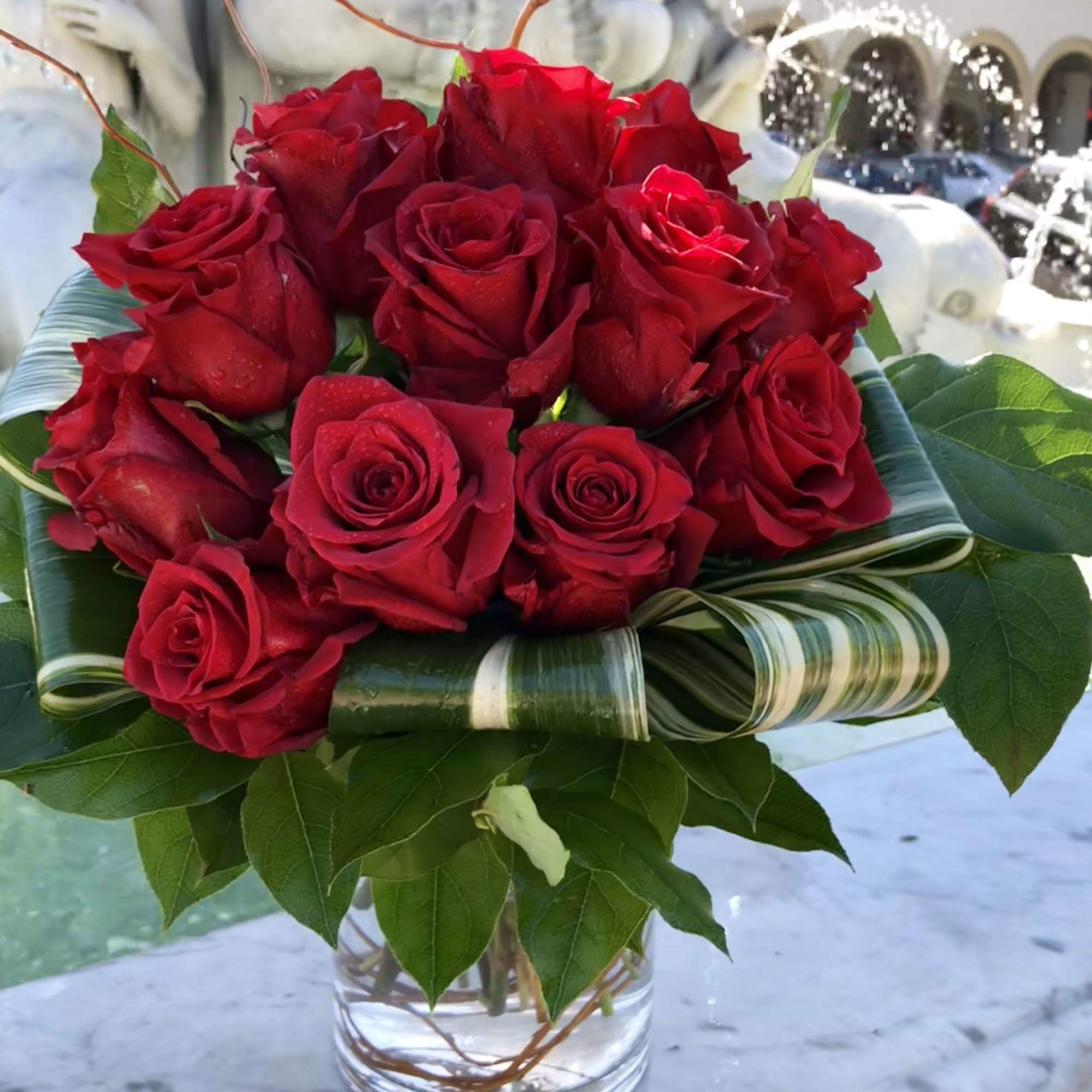 One dozen high quality red roses in a round glass vase, all