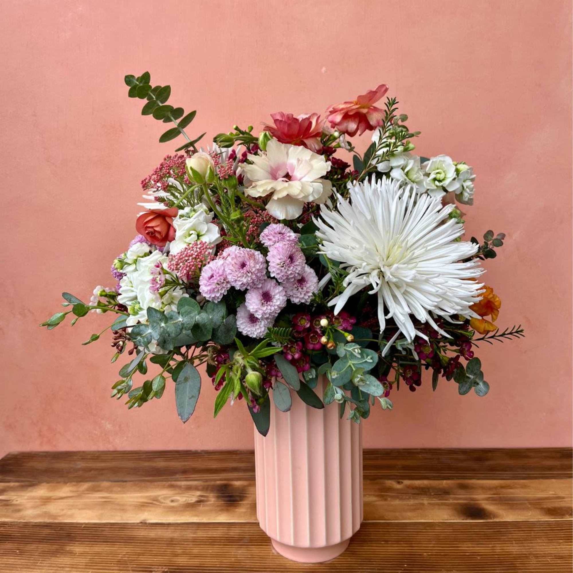 A blossoming arrangement artfully placed in a tall fluted vase that makes