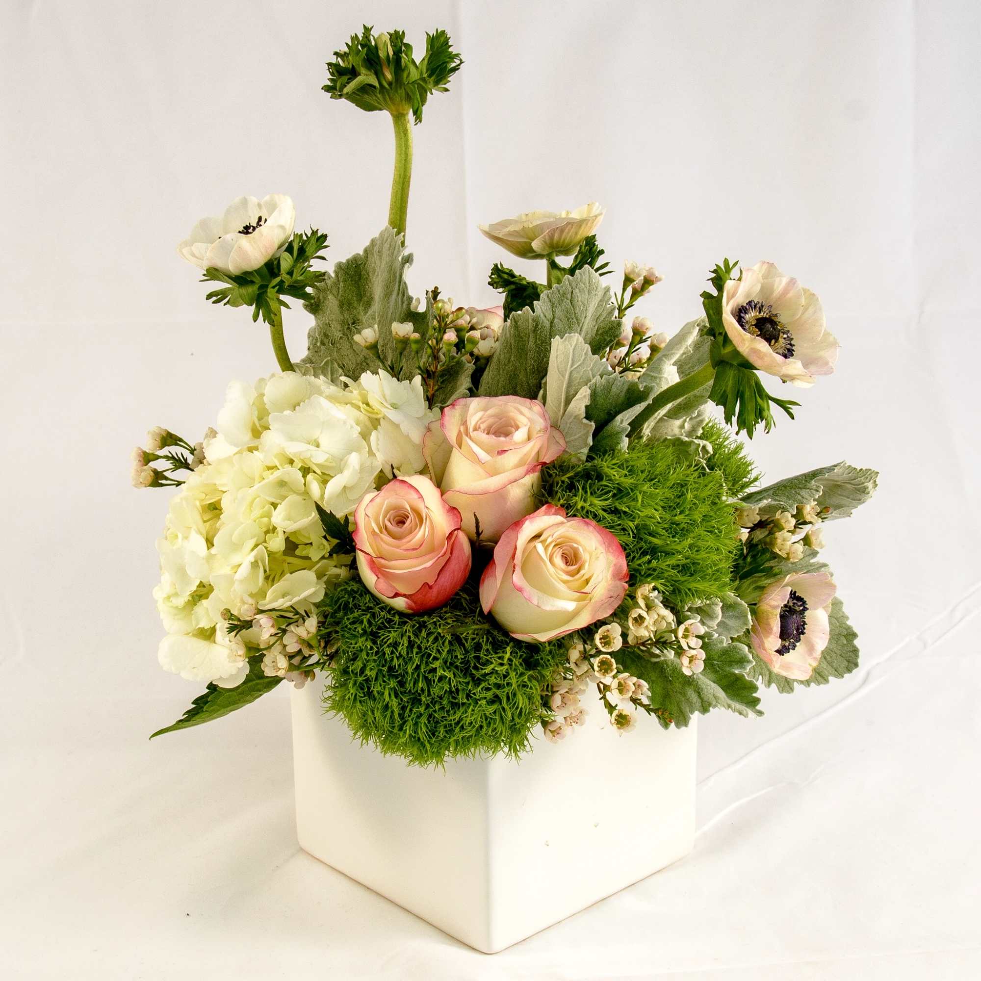 A gathering of unique flowers: peach roses, hydrangea, dianthus, dusty miller, wax