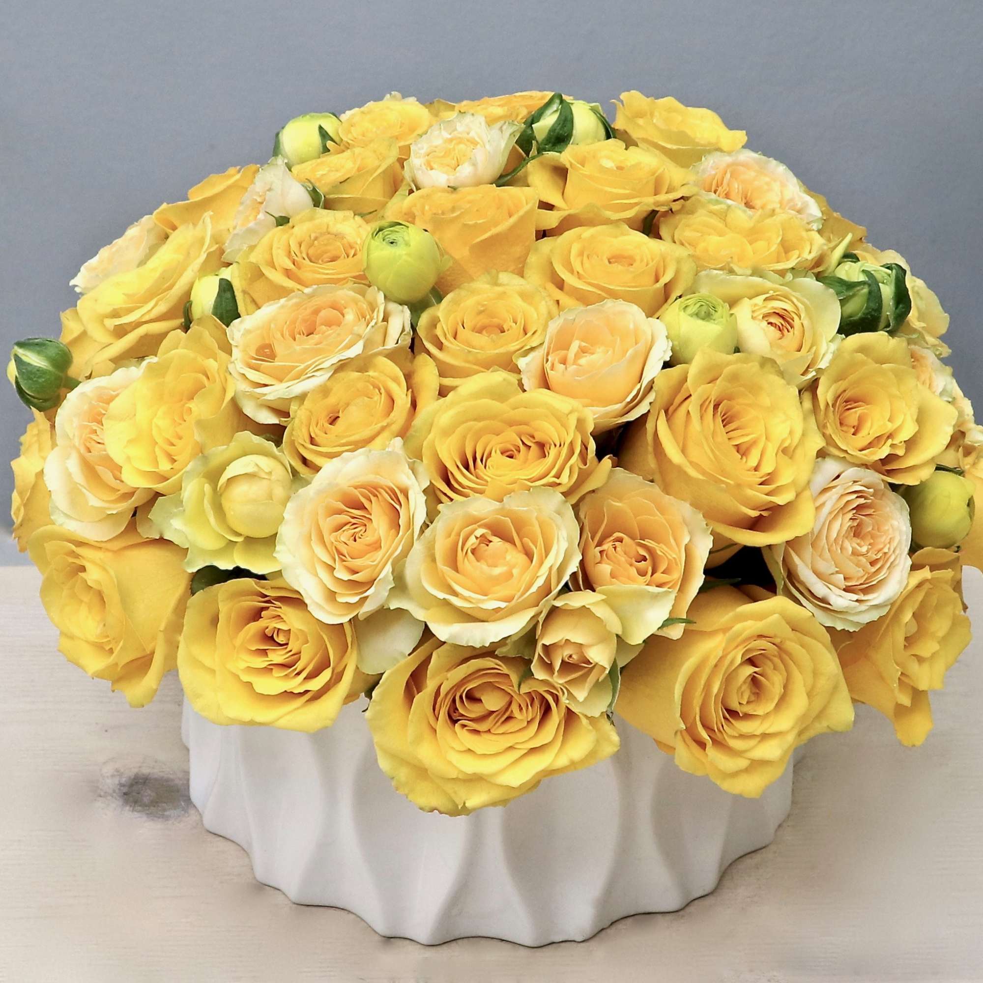 Over two dozen joyful yellow Roses in a round vase. These bright