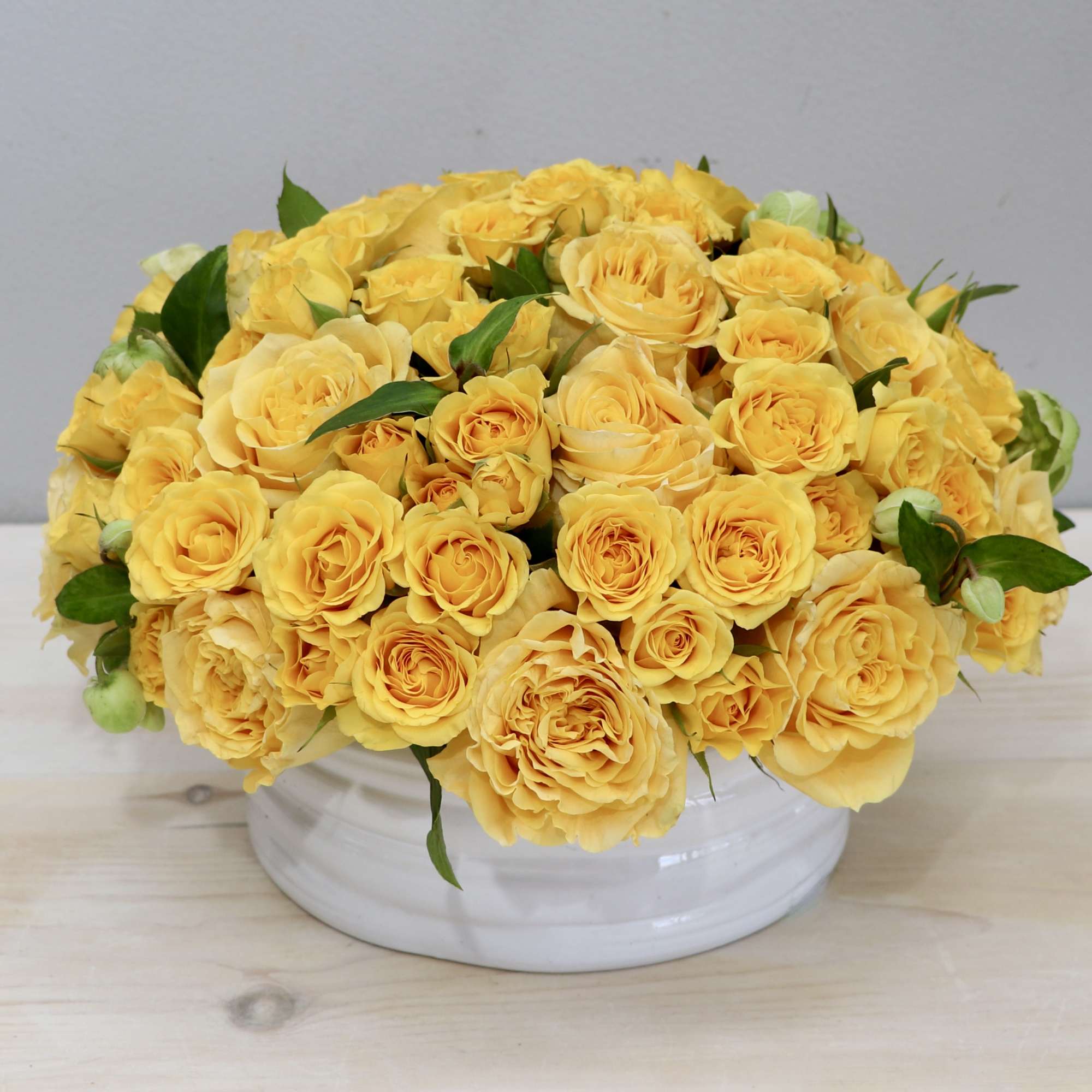 Over two dozen joyful yellow Roses in a round vase. These bright