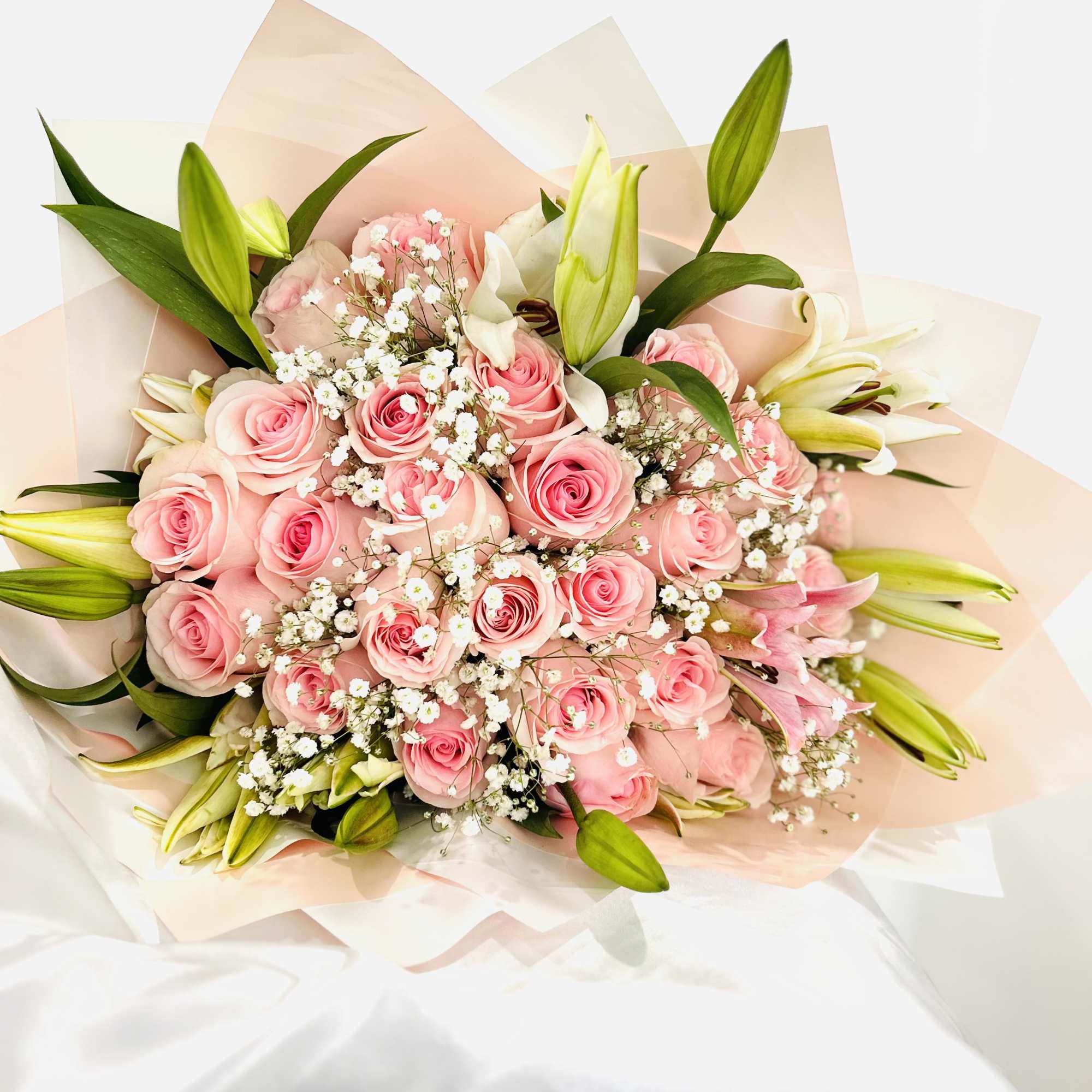 Medium hand wrapped bouquet with roses and lilies.