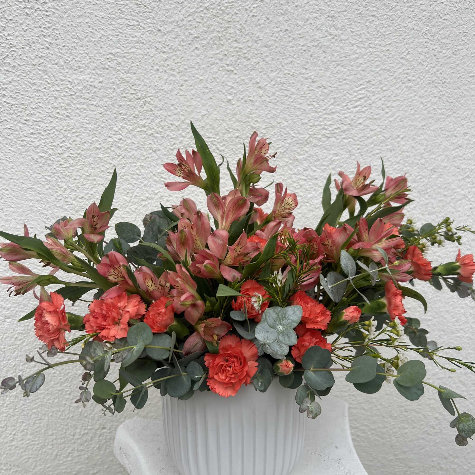 Pinkish Alstroemerias, Bright Orange Carnations, Waxflower and aromatic eucalyptus arranged in a