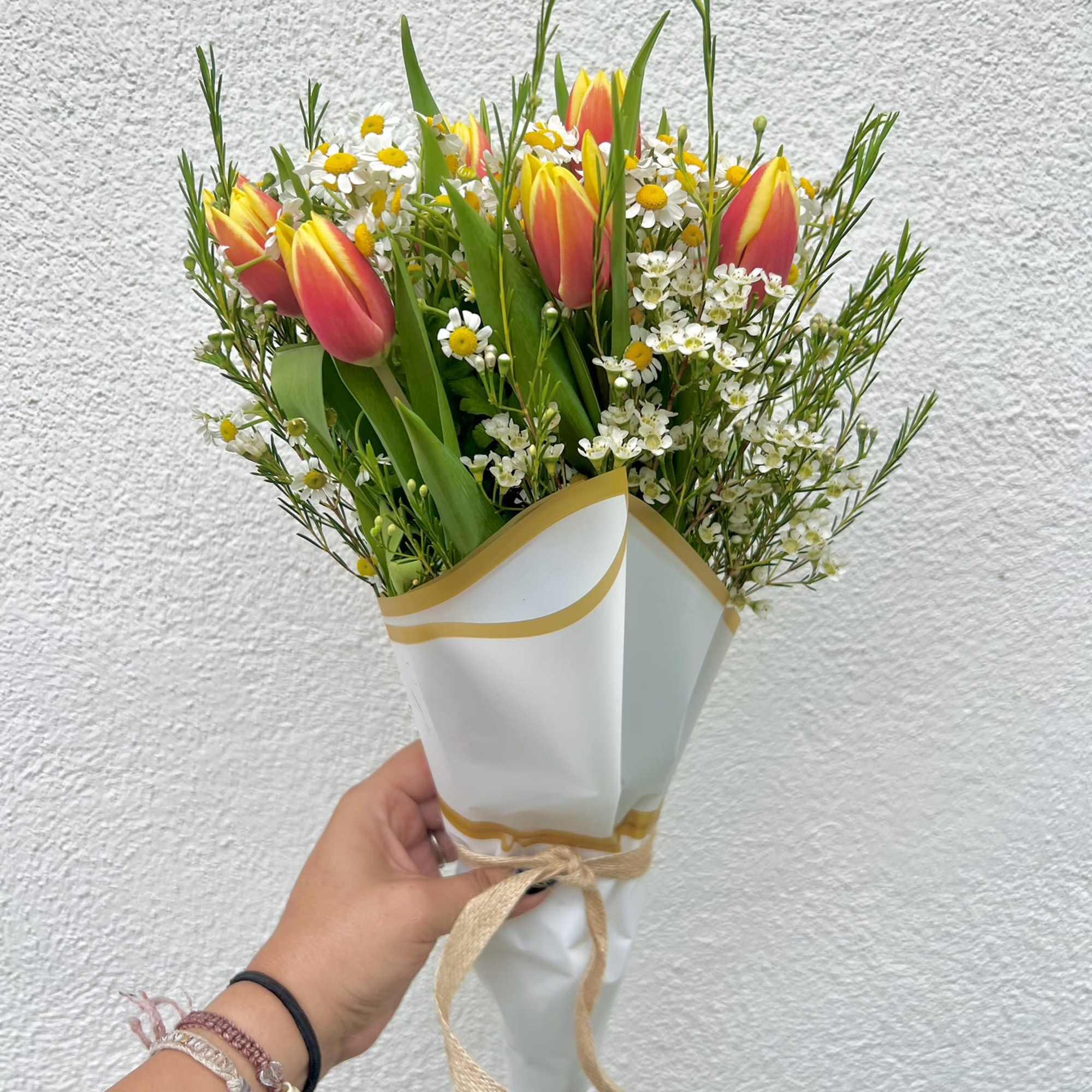 Duo-colored Tulips, Daisies, and Waxflower are handtied to create the perfect arrangement