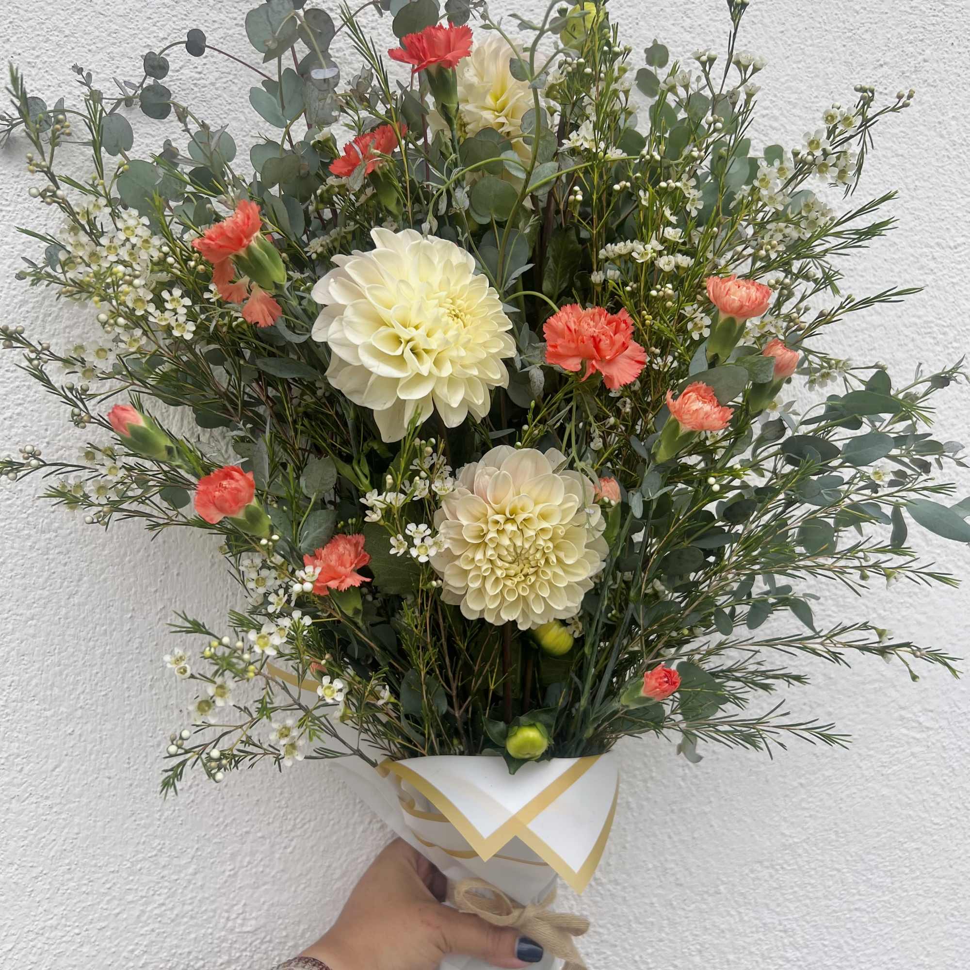 Incredible white/pink Dahlia&rsquo;s flourish alongside bright orange Carnations, Waxflower, and two different
