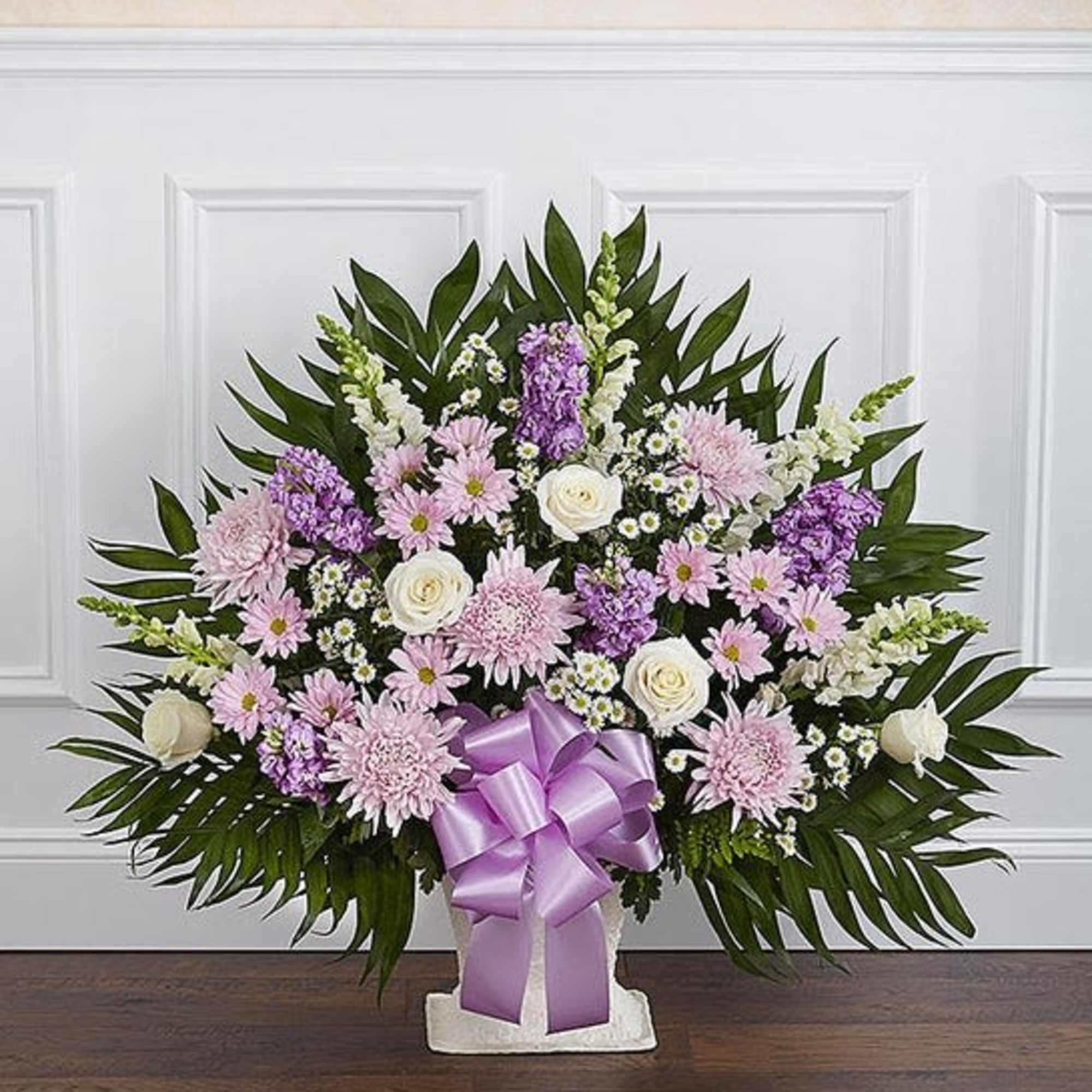 Basket arrangement of lavender daisy poms, football mums, and stock; white roses