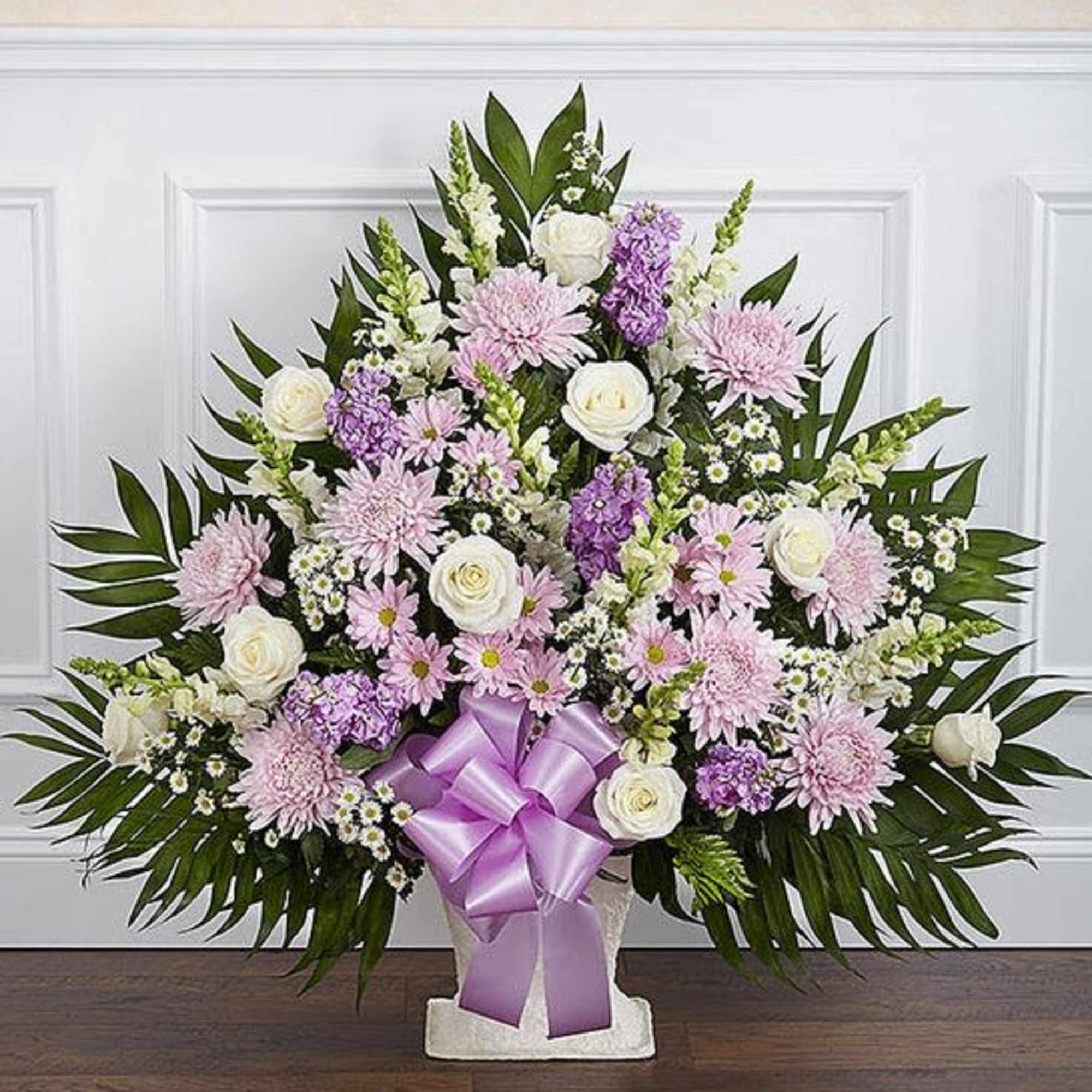 Basket arrangement of lavender daisy poms, football mums, and stock; white roses