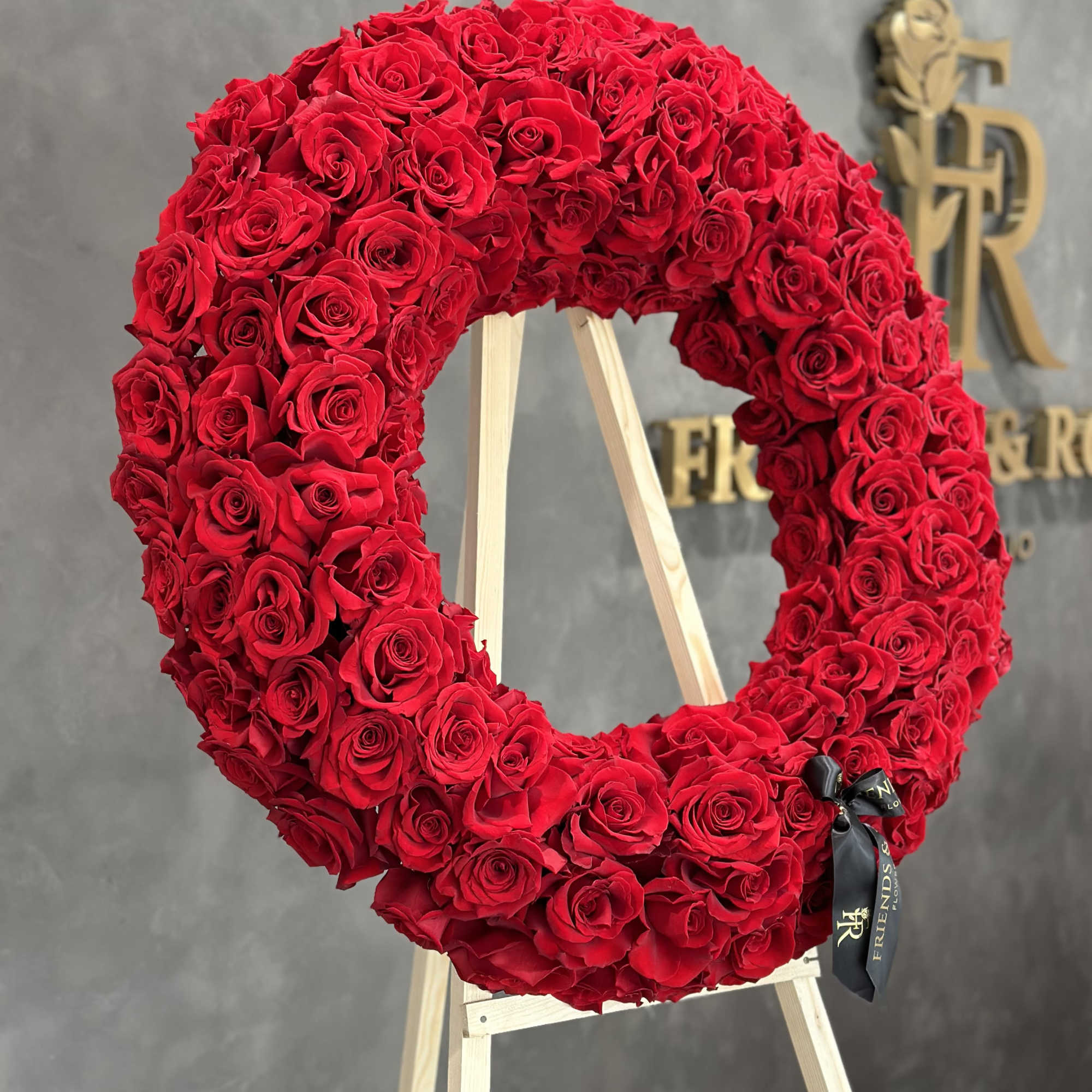 This stunning round wreath, crafted from approximately 150 red roses, symbolizes deep