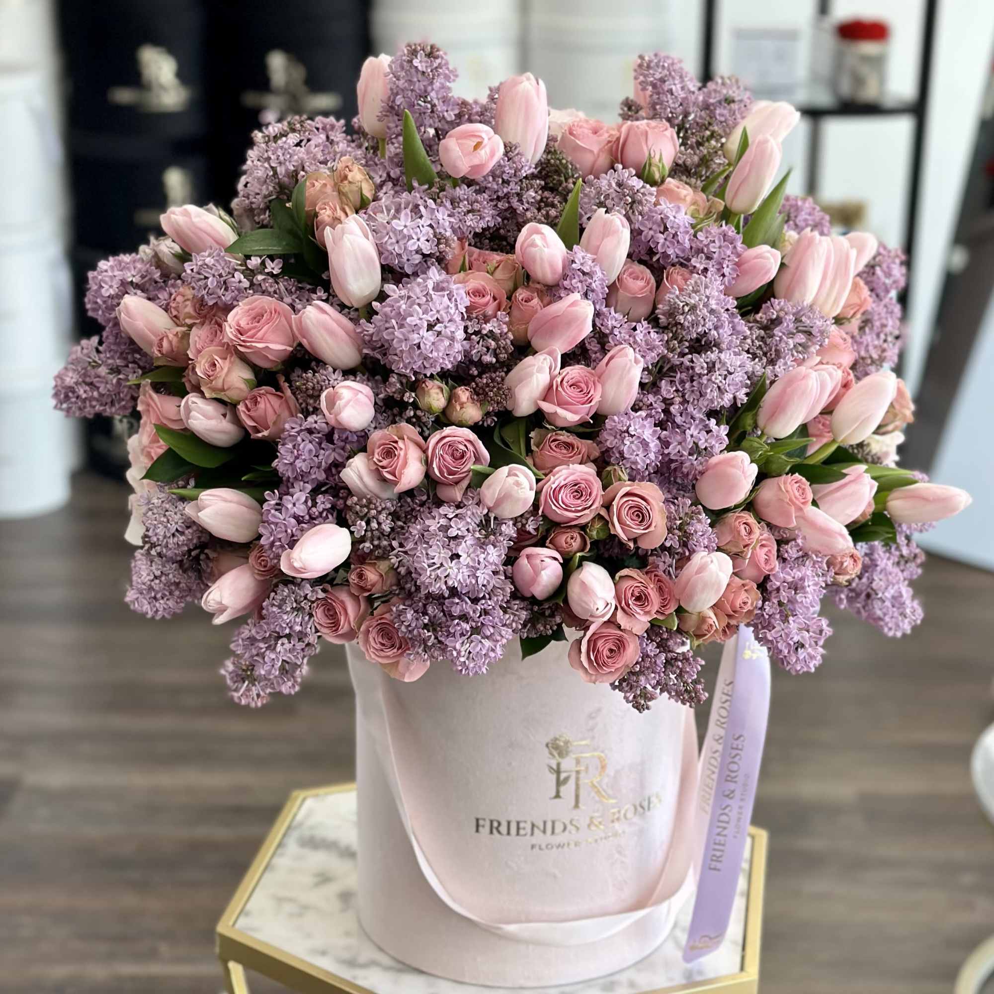 This arrangement is a soft, modern blend of tulips, lilacs, and roses