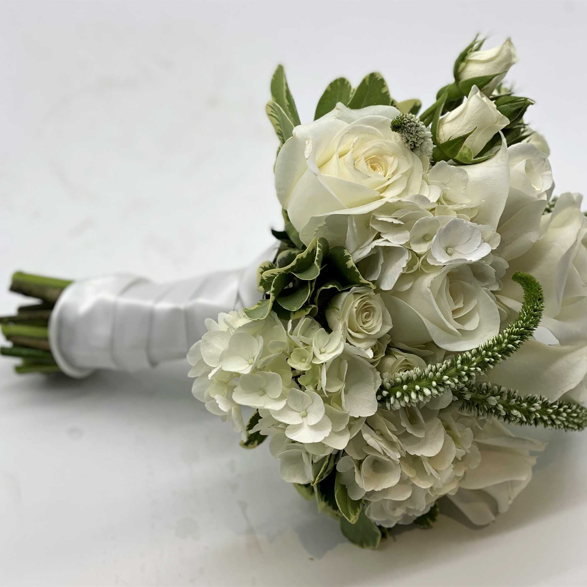 A lush mix of white flowers finished off with a white satin A lush mix of white flowers finished off with a white satin