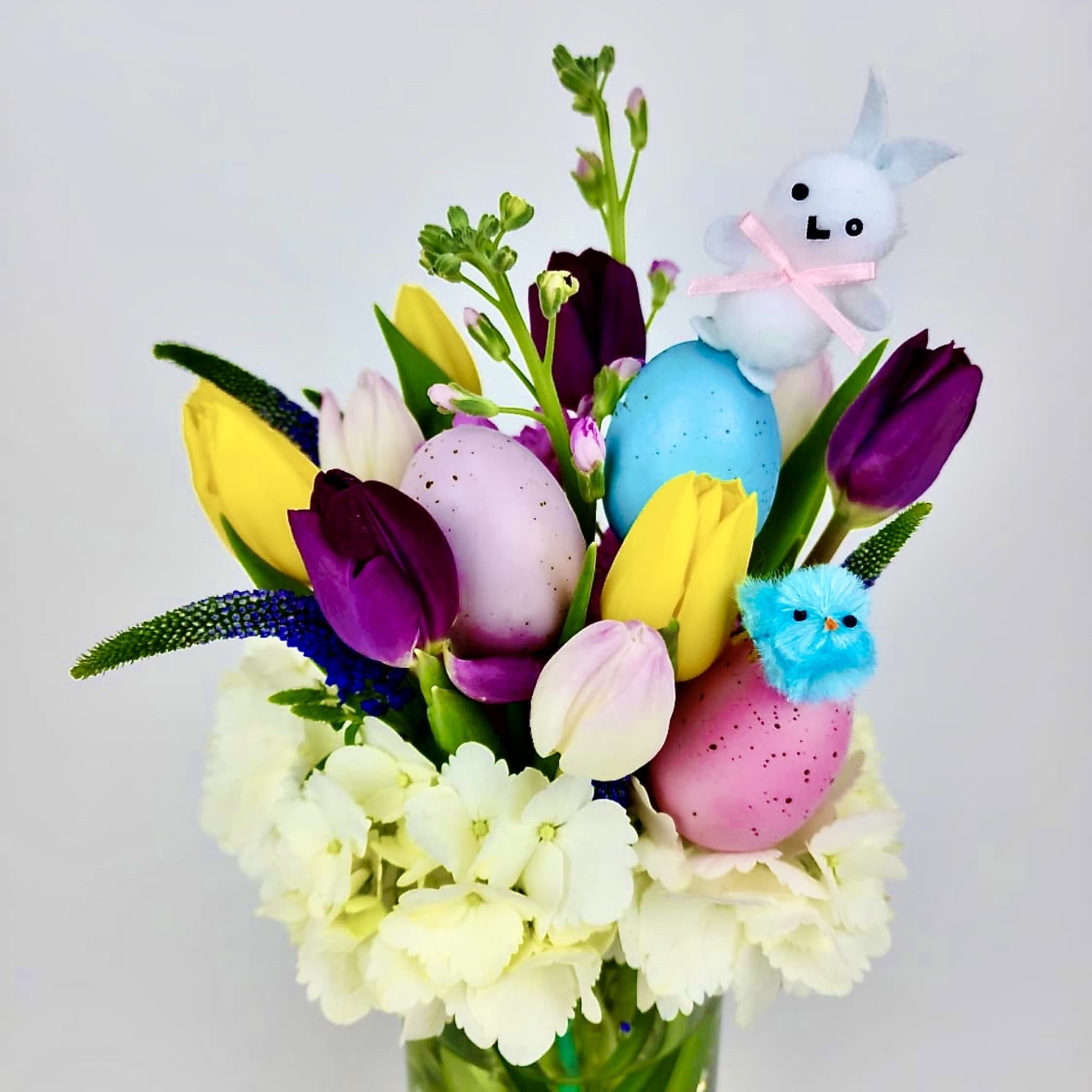 Floral arrangements of colorful Tulips, Veronicas, Stock, white hydrangeas, greens, colorful eggs