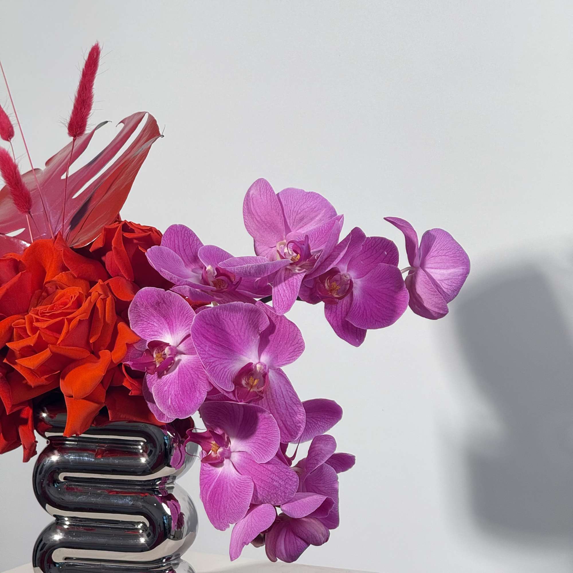 - Elegant purple orchids paired with bold, red painted leaves
- Unique silver