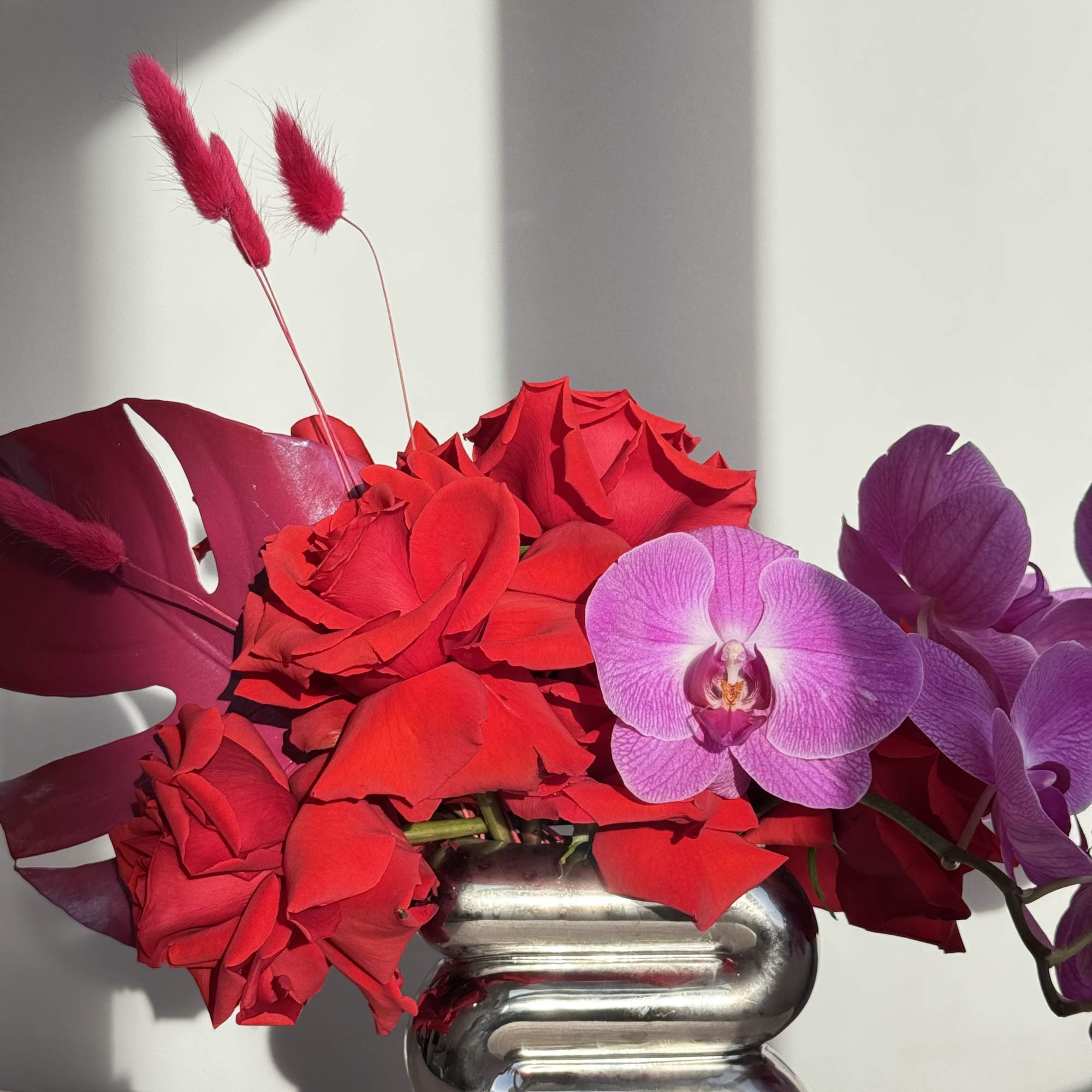 - Elegant purple orchids paired with bold, red painted leaves
- Unique silver