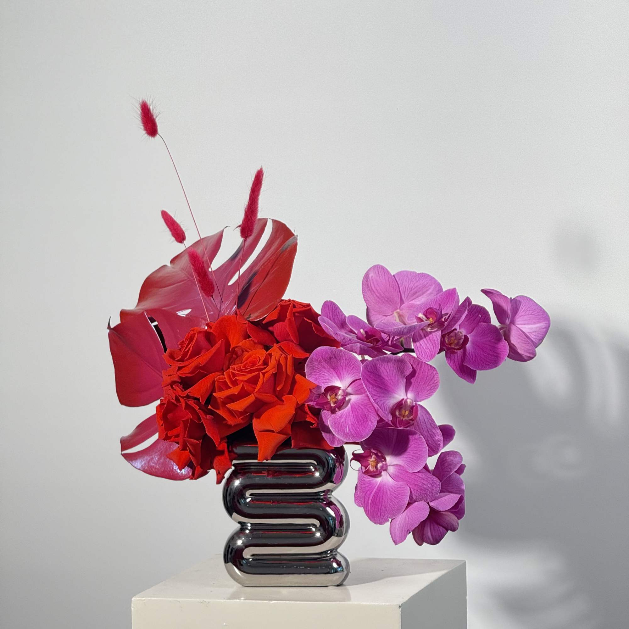 - Elegant purple orchids paired with bold, red painted leaves
- Unique silver