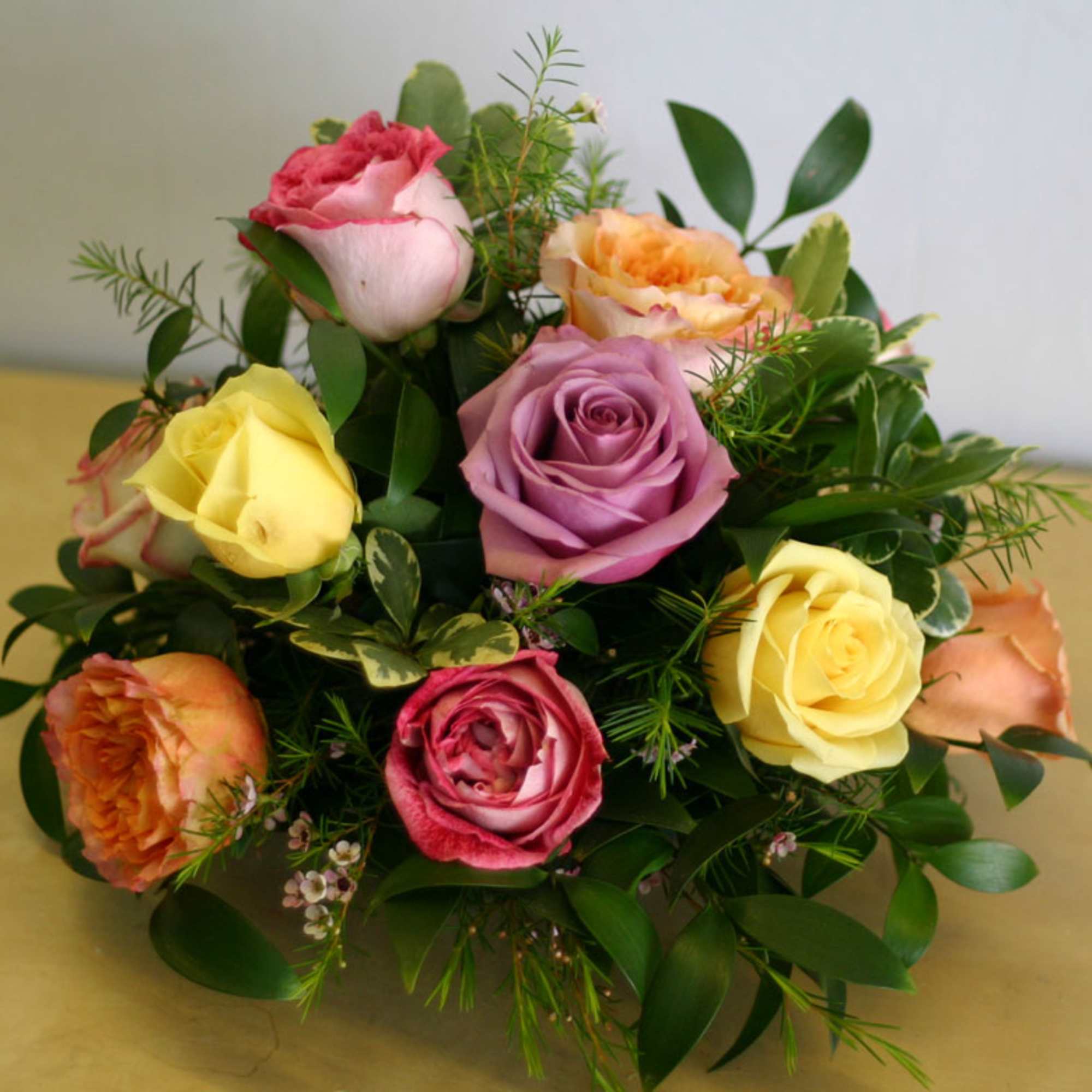 One dozen mixed color roses arranged in a lower all-around centerpiece style