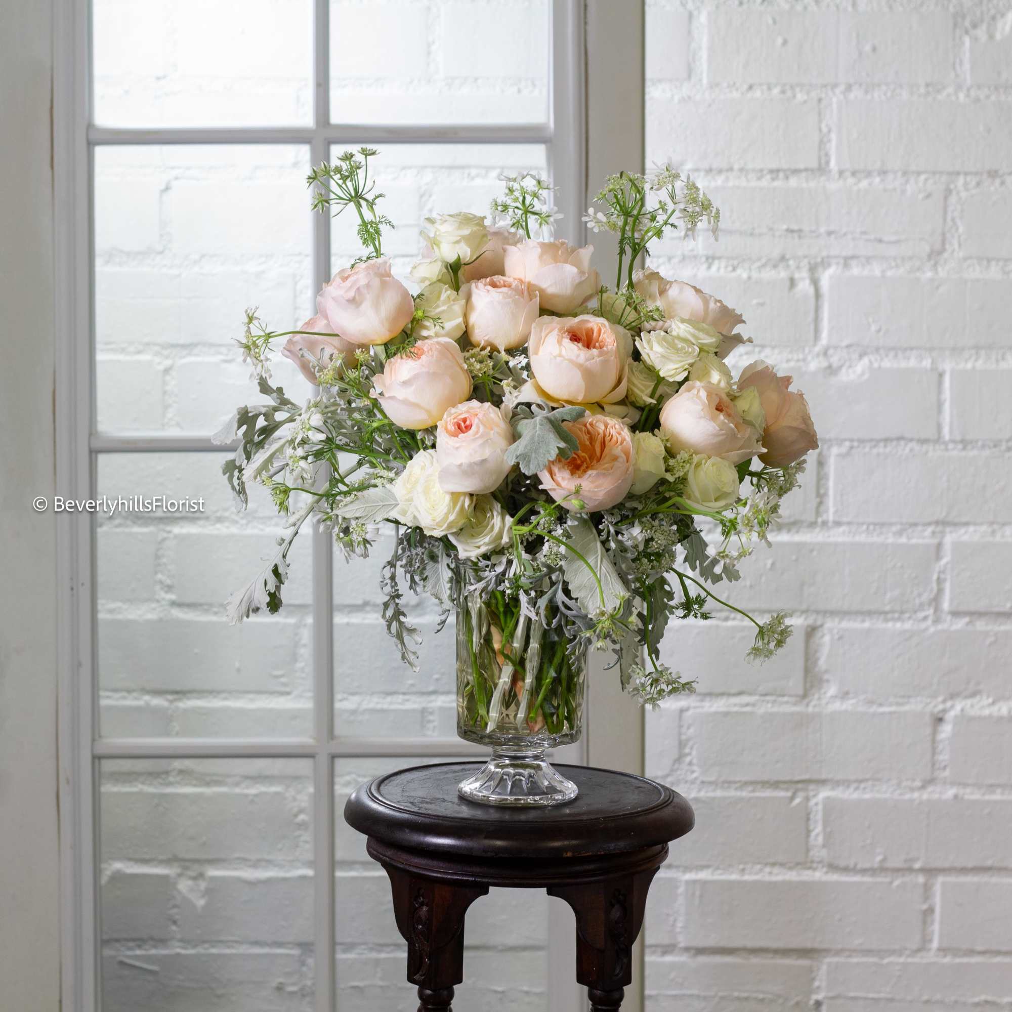 Nestled in a short glass vase, creamy romantic garden roses take center Nestled in a short glass vase, creamy romantic garden roses take center