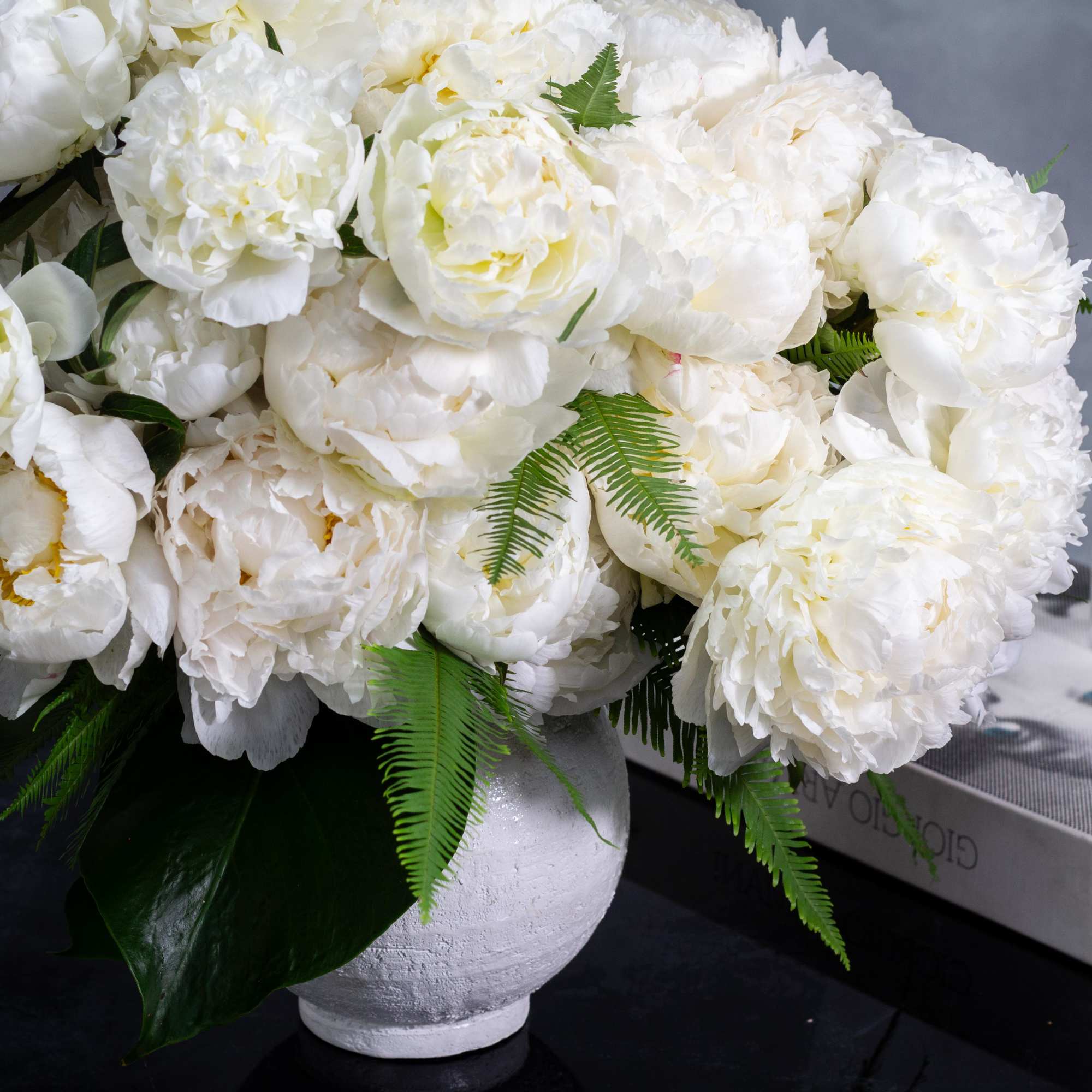 A lavish arrangement of over 20 pristine white peonies nestled within  A lavish arrangement of over 20 pristine white peonies nestled within