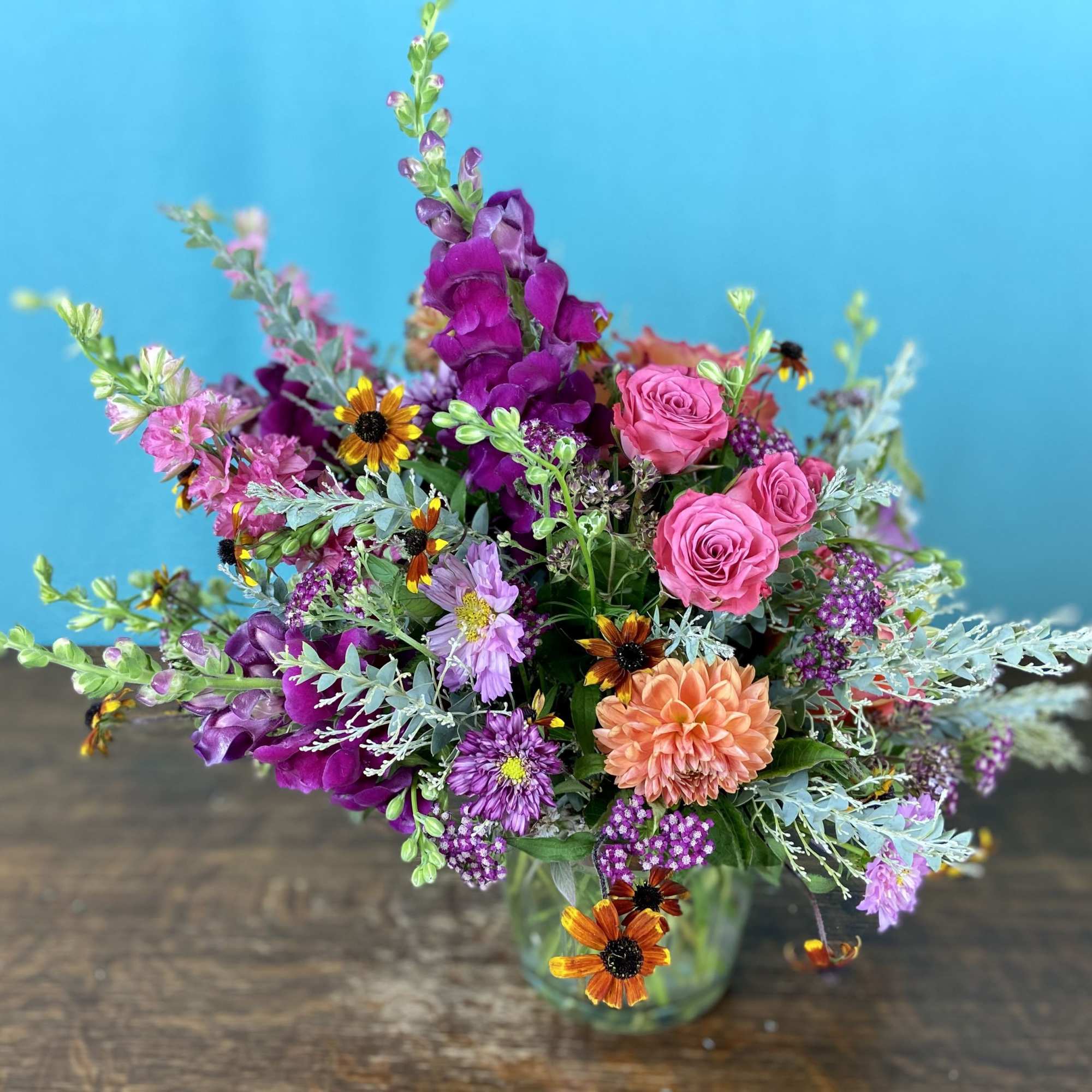 Low and lush floral arrangement in a short vase.  Typically includes