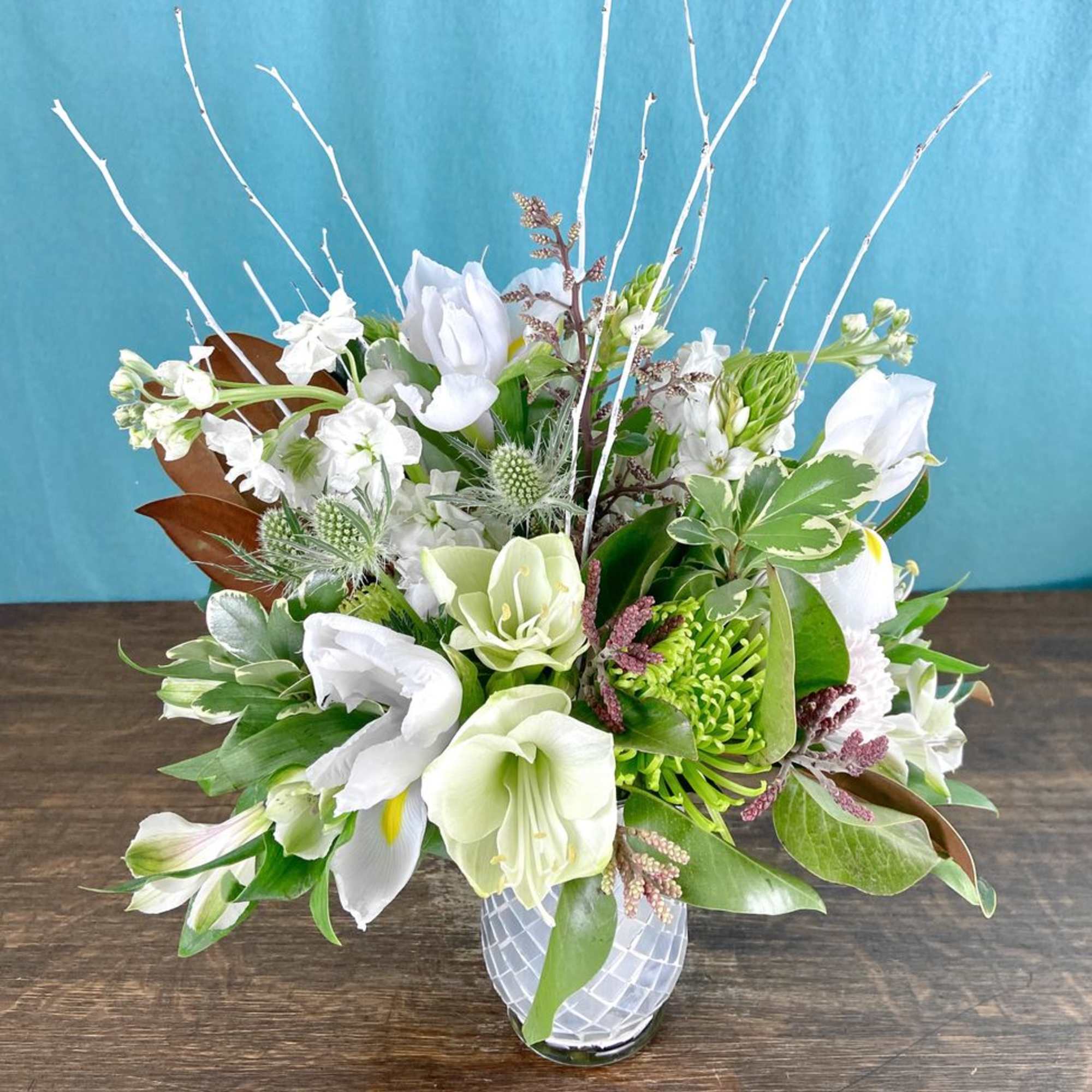 Low floral arrangement in seasonal colors, flowers and greenery.  Will likely