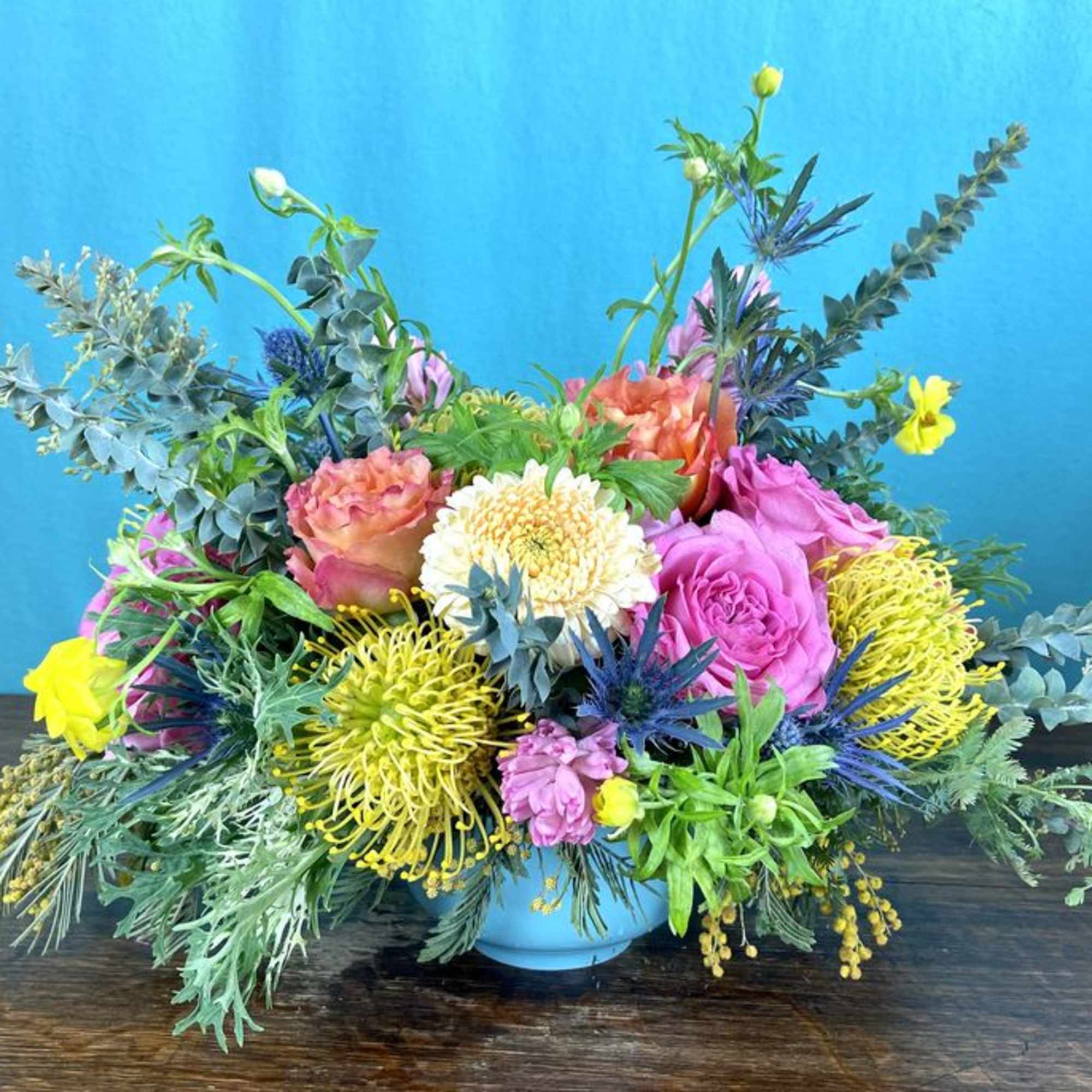 Low floral arrangement in seasonal colors, flowers and greenery.  Will likely