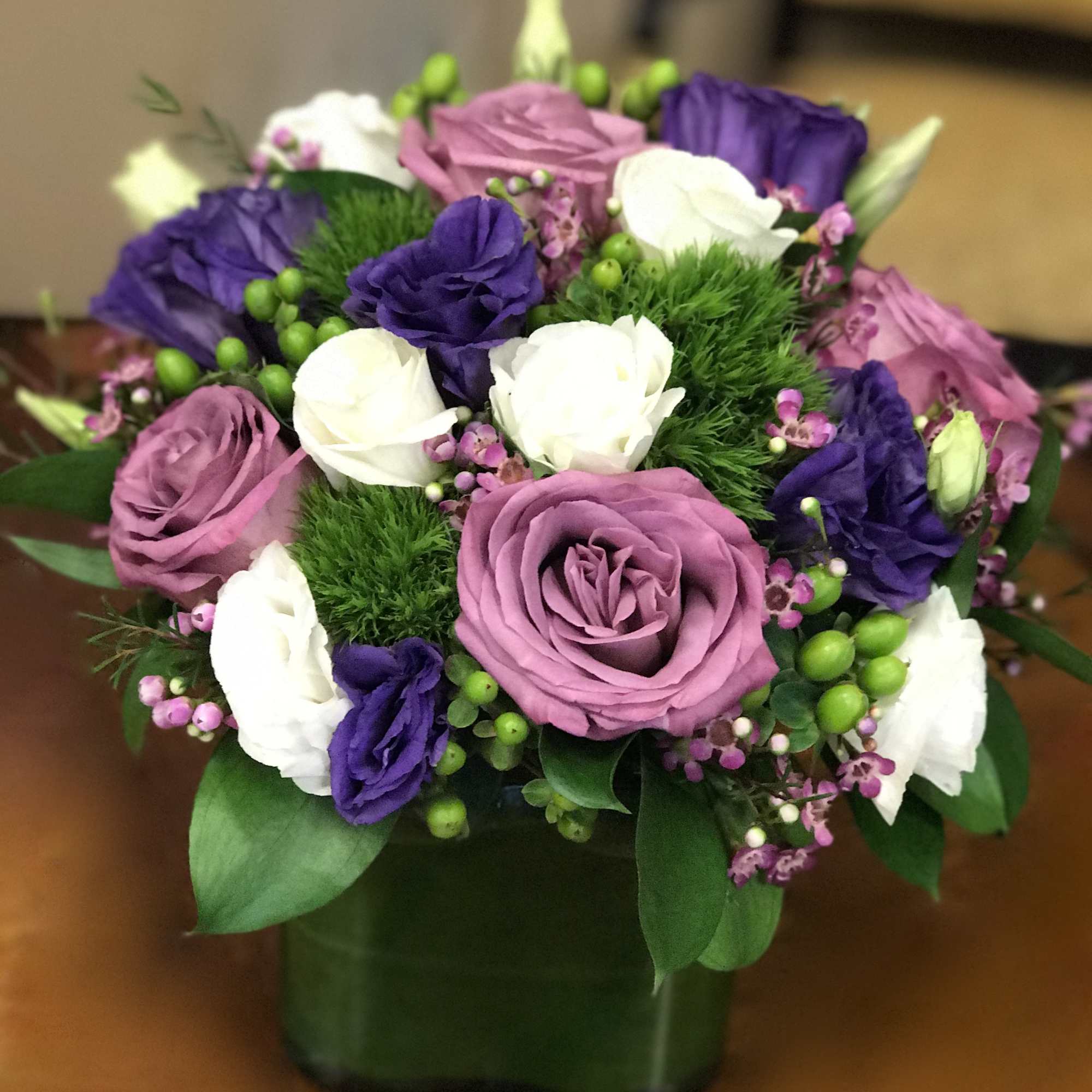 Beautiful modern cube vase with purple roses, purple lisianthus, white spray roses