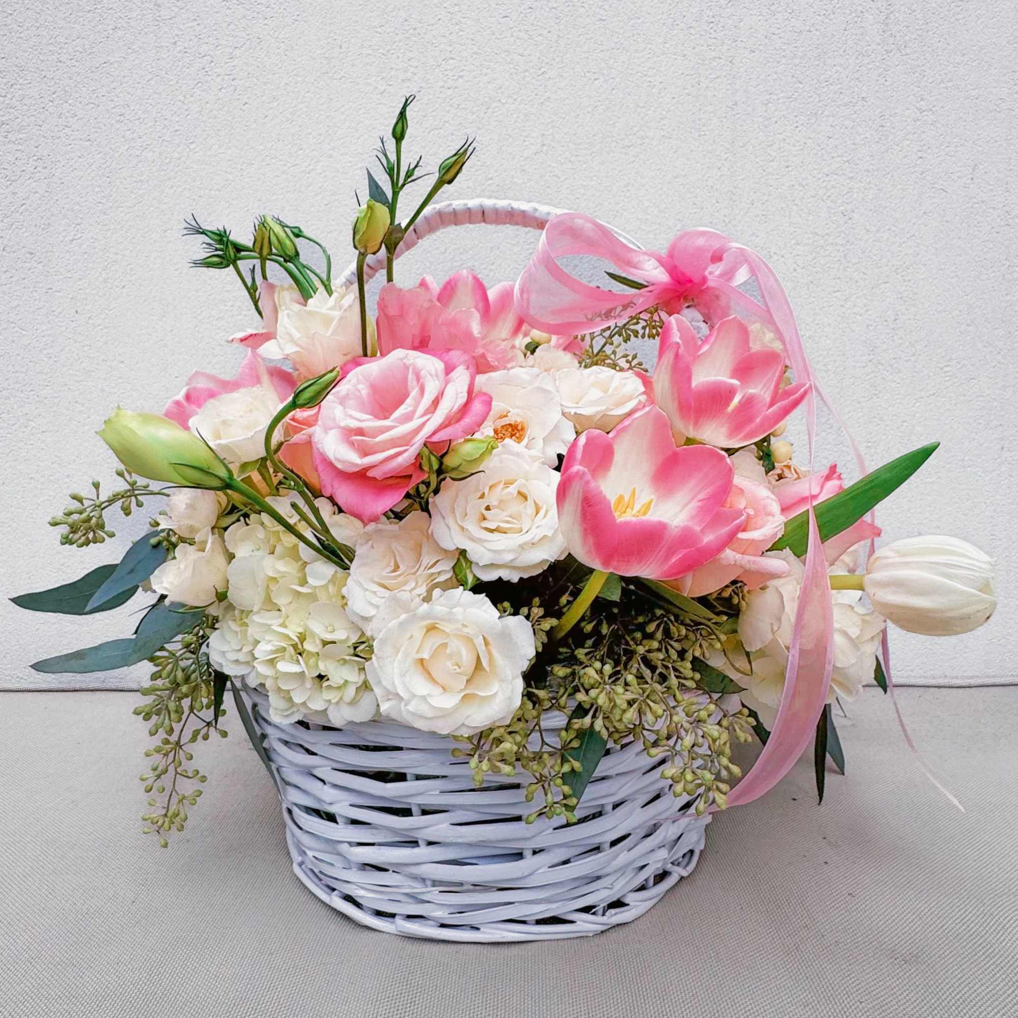 This charming basket bouquet brims with delicate pink roses, creamy white spray This charming basket bouquet brims with delicate pink roses, creamy white spray