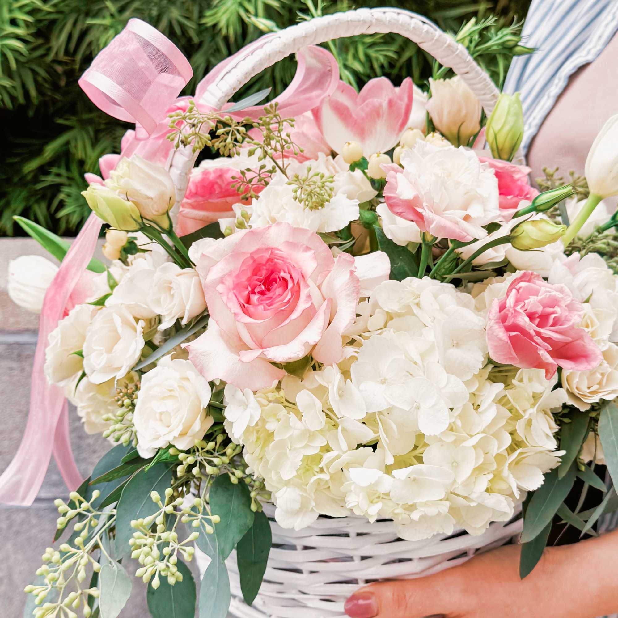 This charming basket bouquet brims with delicate pink roses, creamy white spray This charming basket bouquet brims with delicate pink roses, creamy white spray
