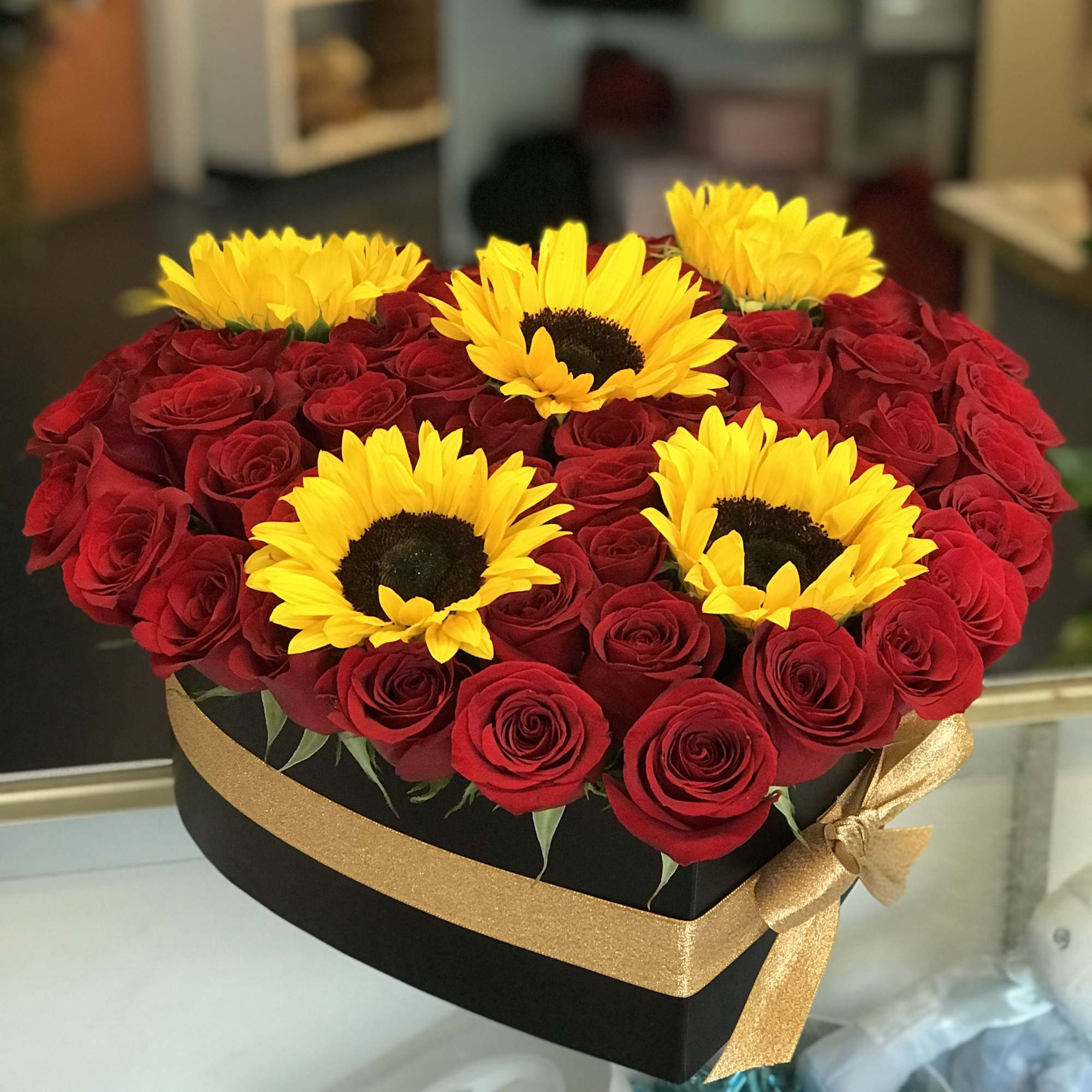This heart box arrangement comes in all red roses and five sunflowers.