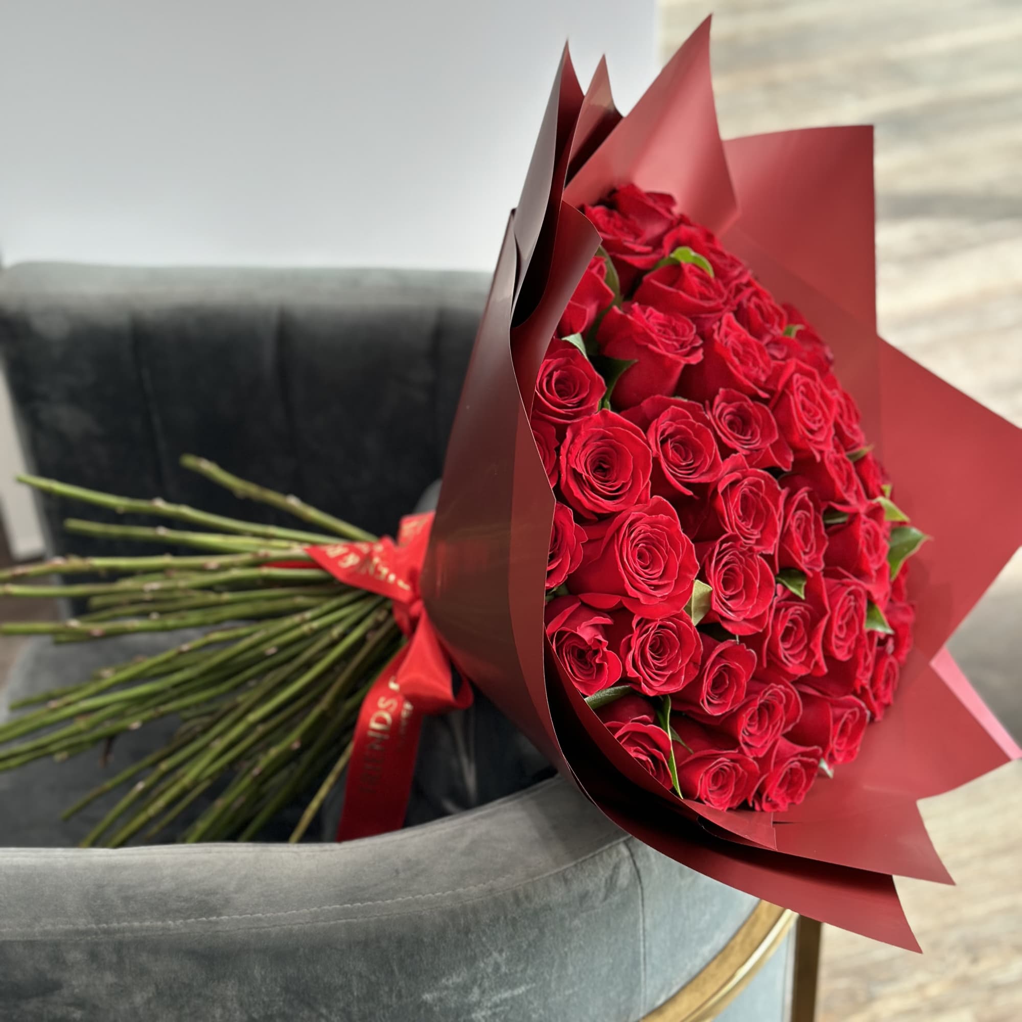 A stunning bouquet of 50 red roses wrapped in paper is a