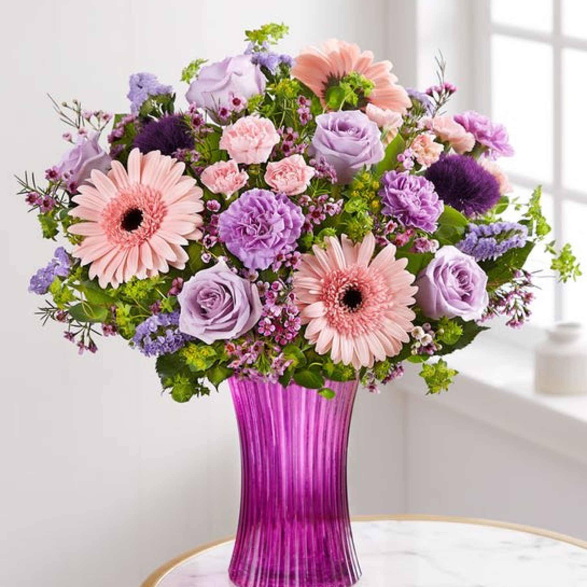 The arrangement with lavender roses, carnations and statice; pink Gerbera daisies and