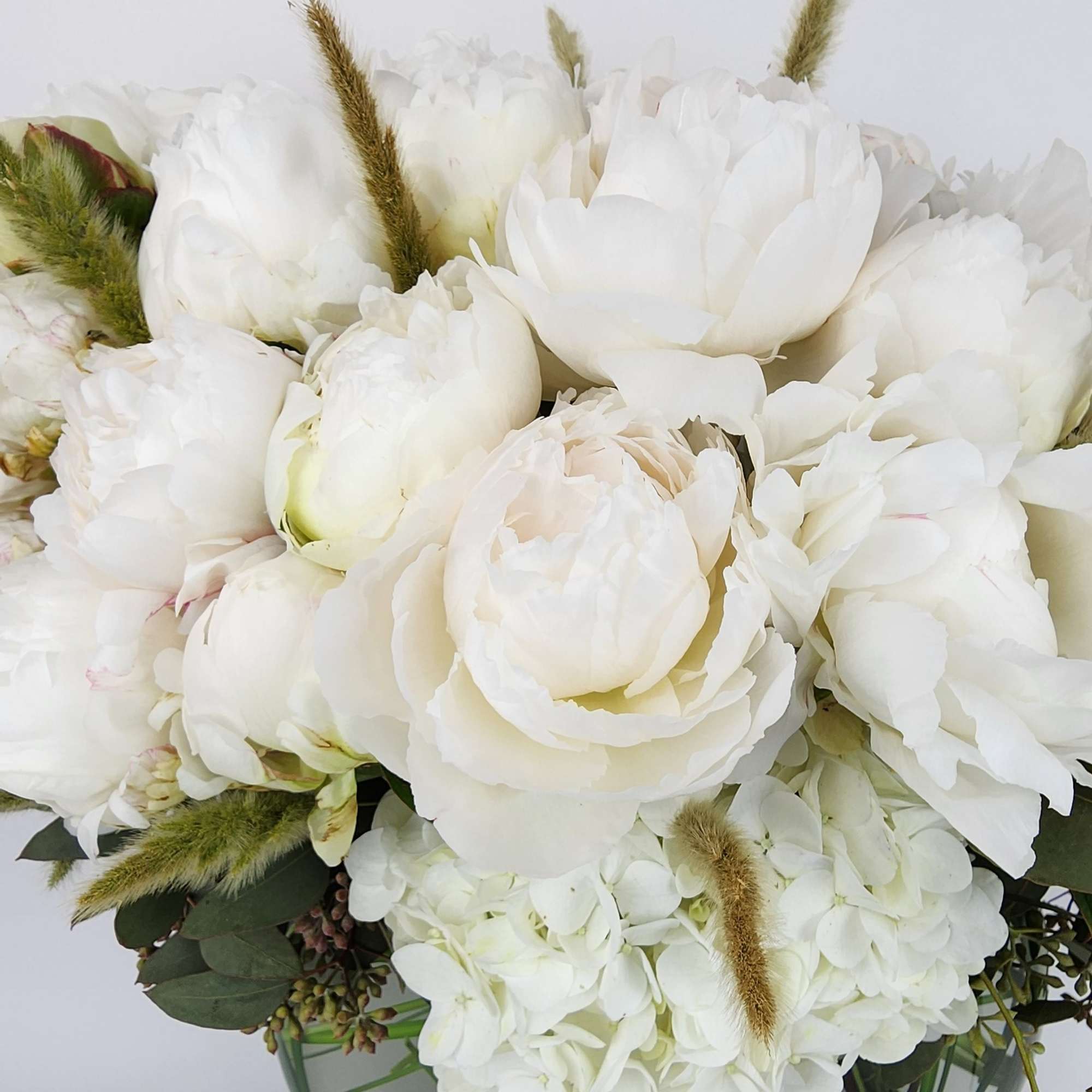 In a clear vase, an arrangement made of 2 dozen peonies, a In a clear vase, an arrangement made of 2 dozen peonies, a
