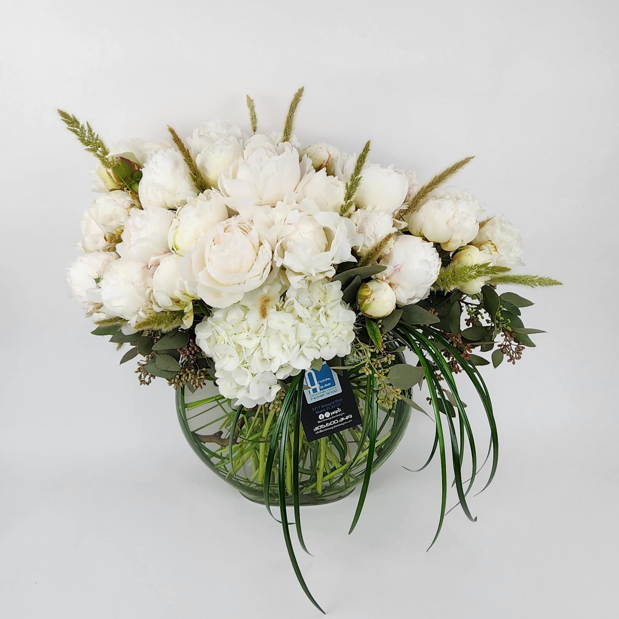 In a clear vase, an arrangement made of 2 dozen peonies, a In a clear vase, an arrangement made of 2 dozen peonies, a