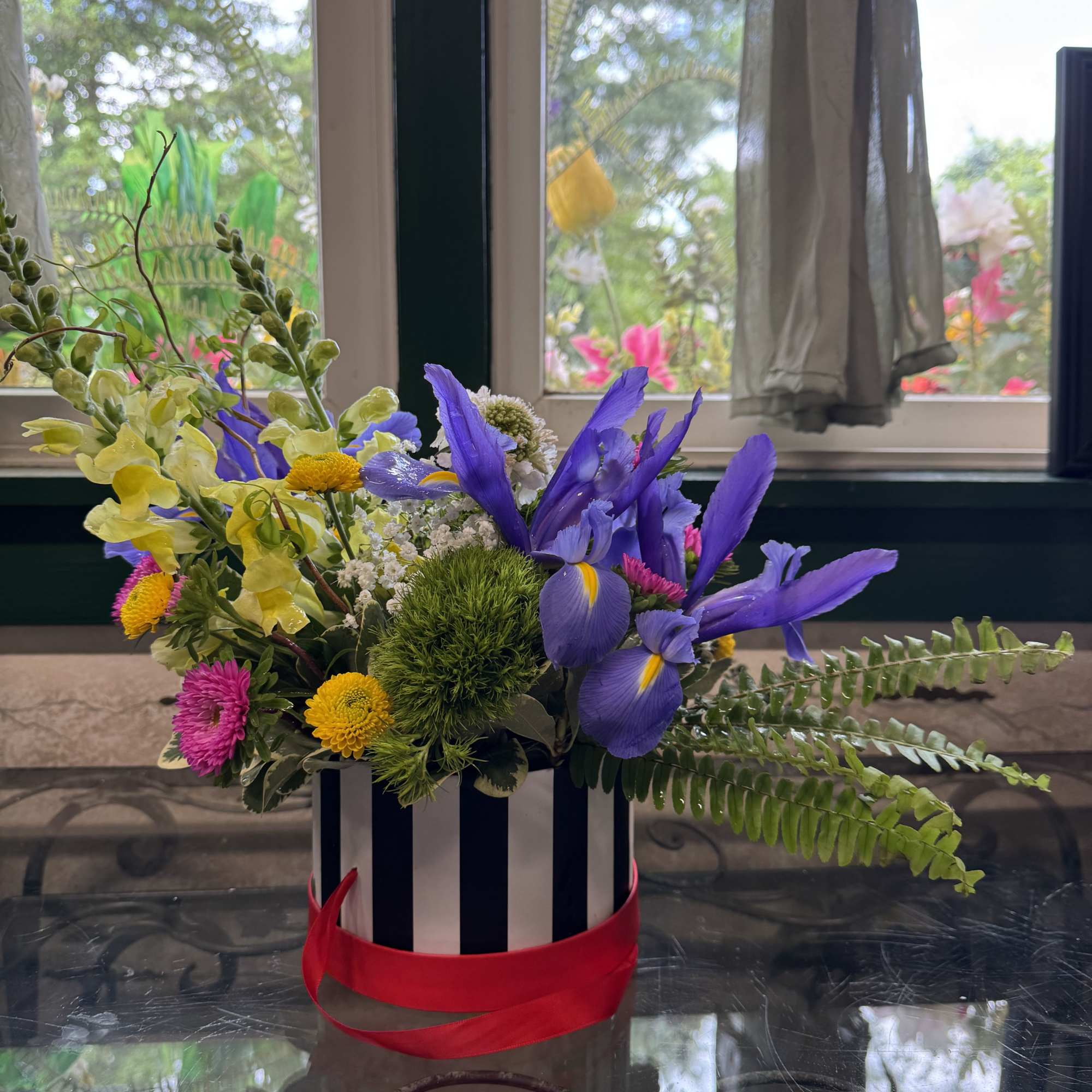 Red,white and black hatbox with a designer&rsquo;s mix flowers arrangement.